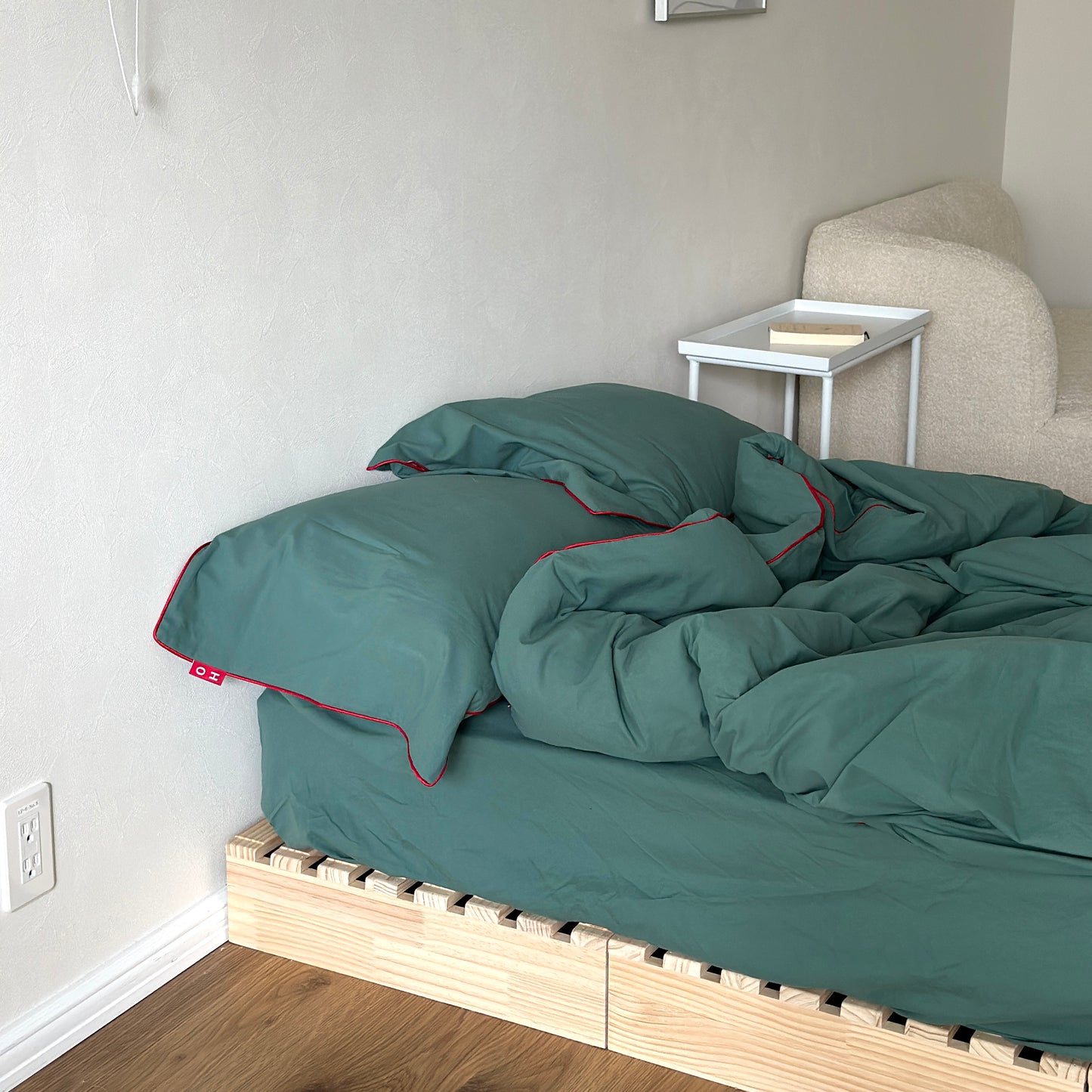 グリーンのベッドカバーが掛かったベッドがある部屋