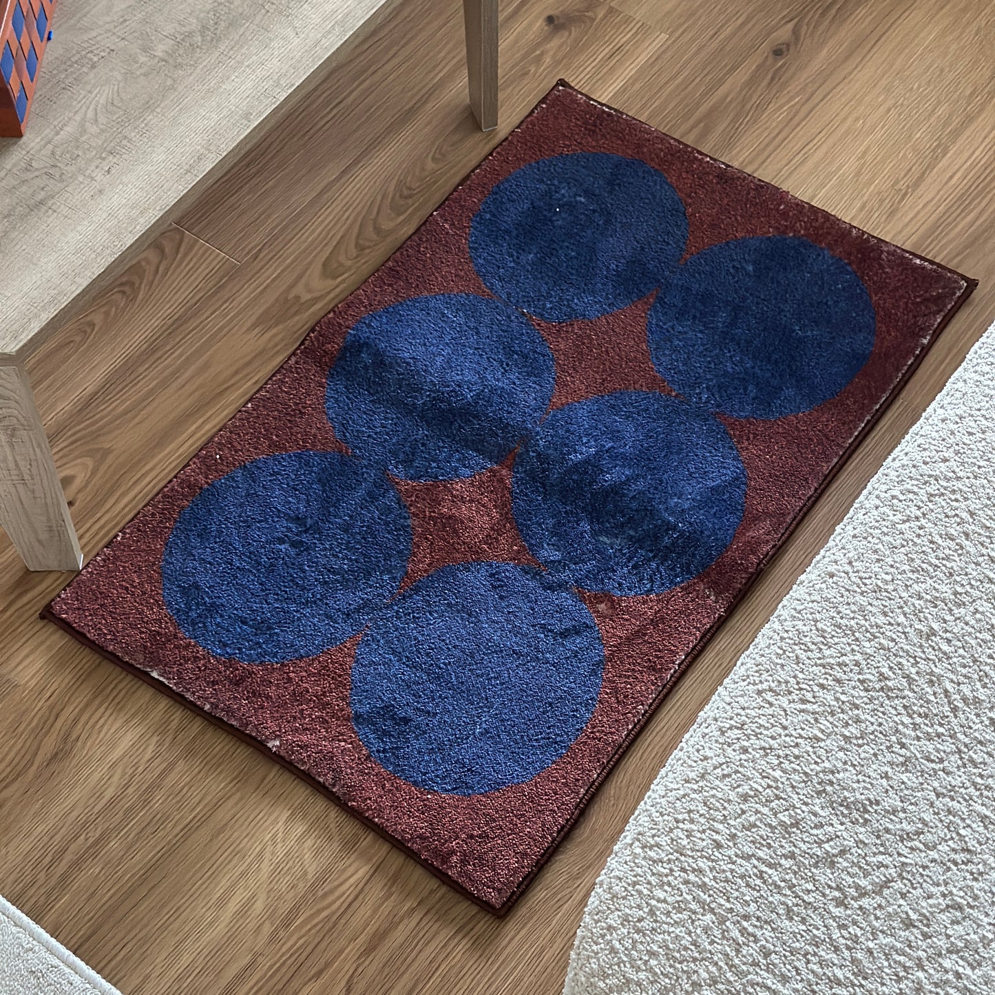 青丸が6個描かれたモダンなミニラグをソファとローテーブルの間に敷いている様子