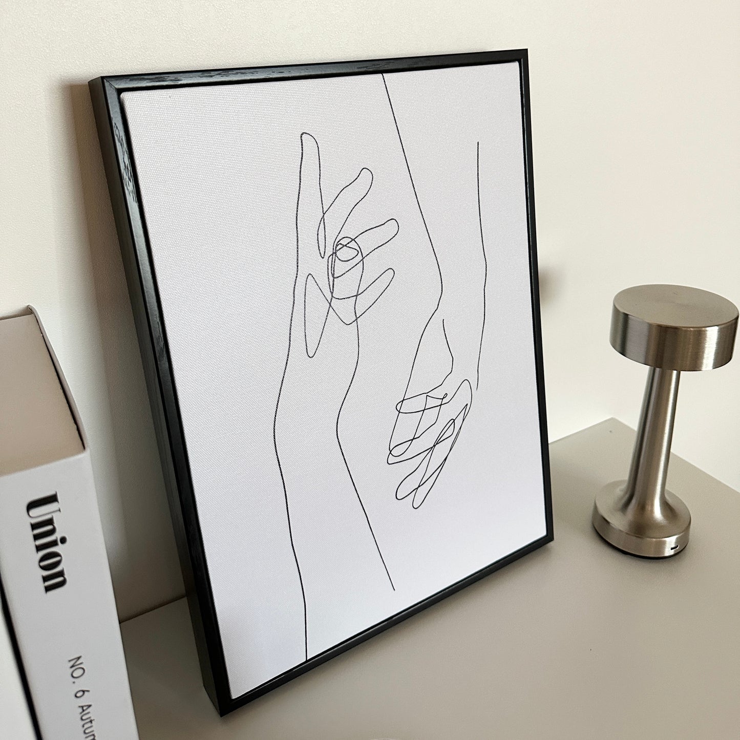 2つの手が描かれたアートとその横にライトと本が置かれている