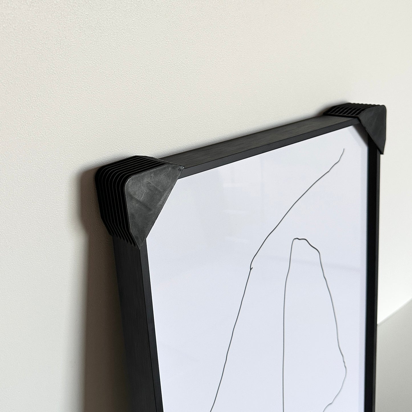 額縁の角にカバーがされている2つの手が描かれたアート