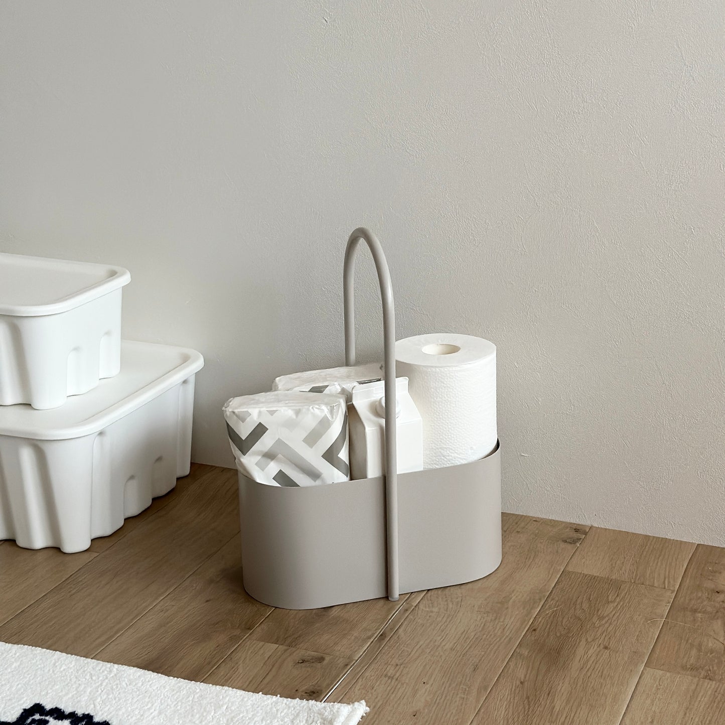 取手付きのベージュのコンテナにトイレットペーパーやティッシュが収納されている様子