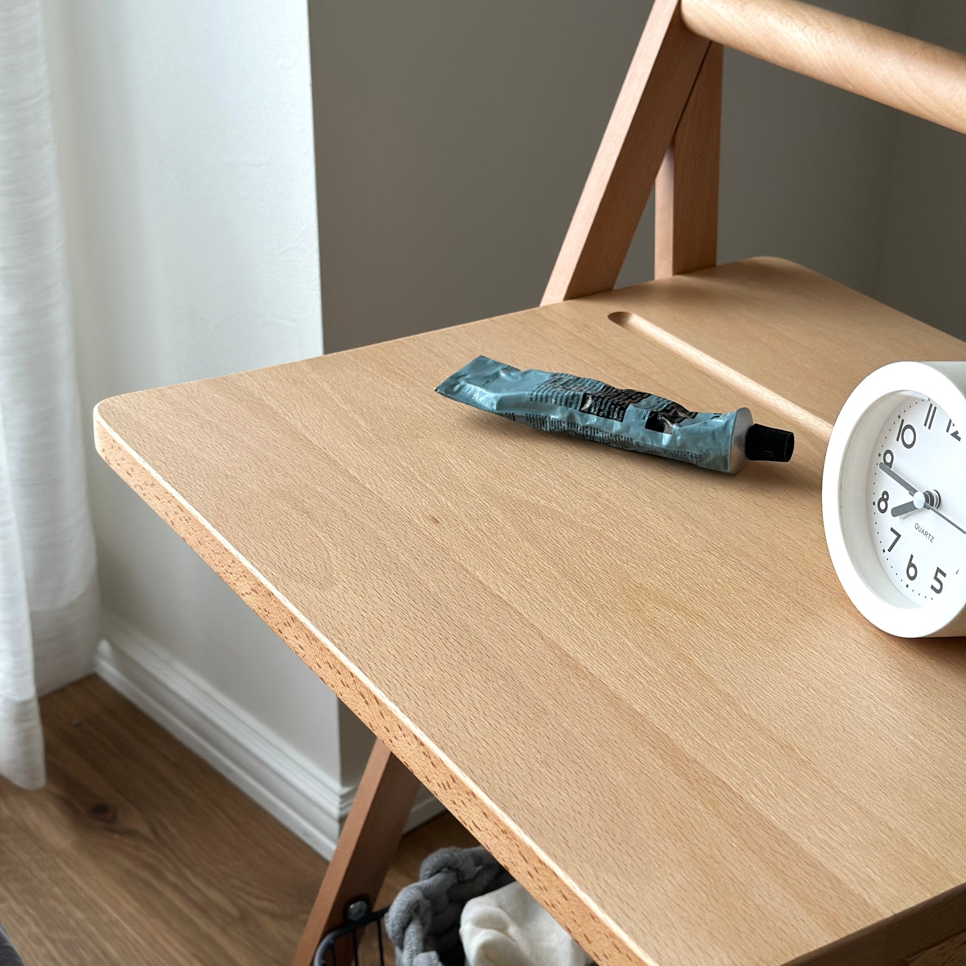 ナチュラルウッドのサイドテーブルの上にハンドクリームと時計が置かれてある