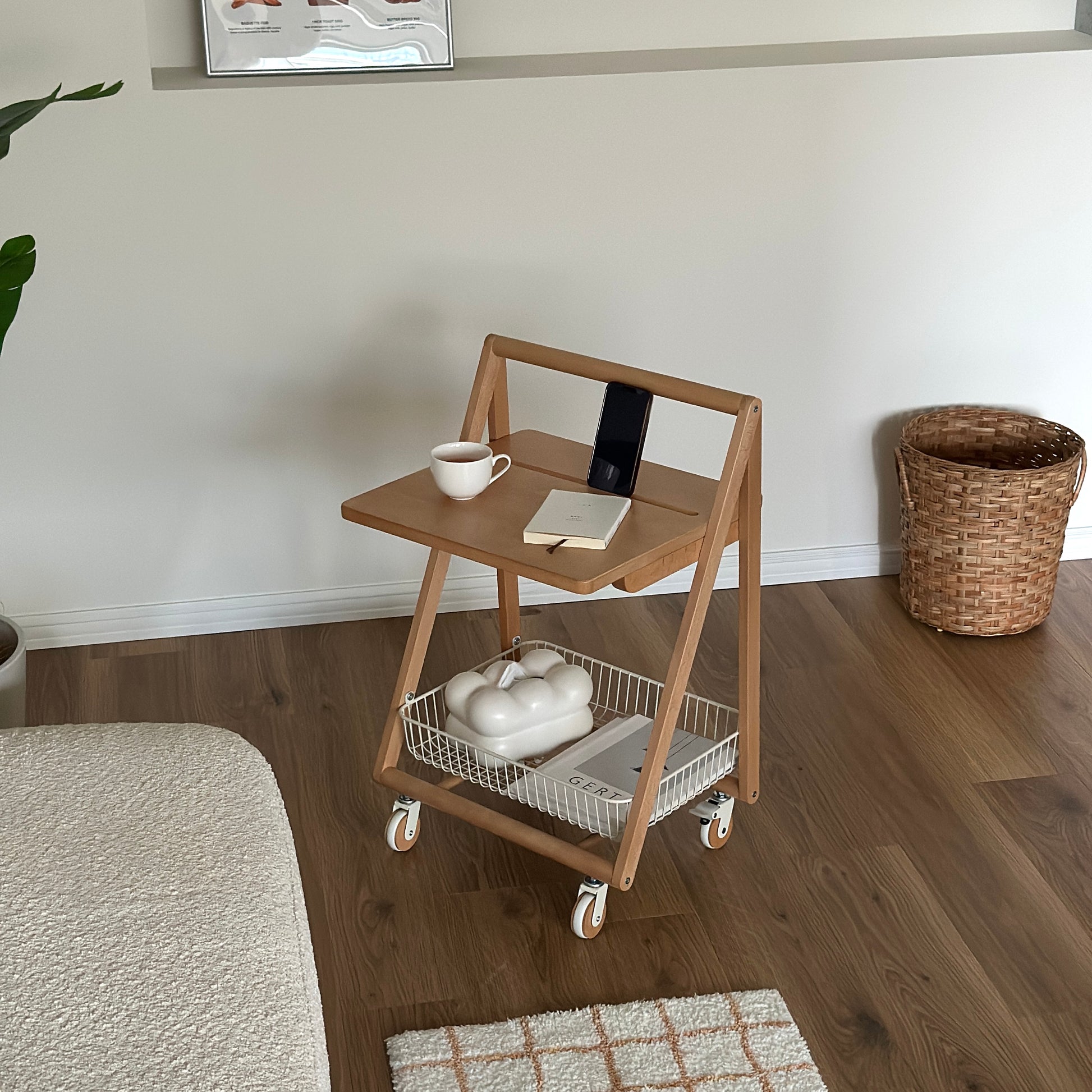 ナチュラルウッドのキャスター付きサイドテーブルの上にティーカップと文庫本、スマホが置かれてある