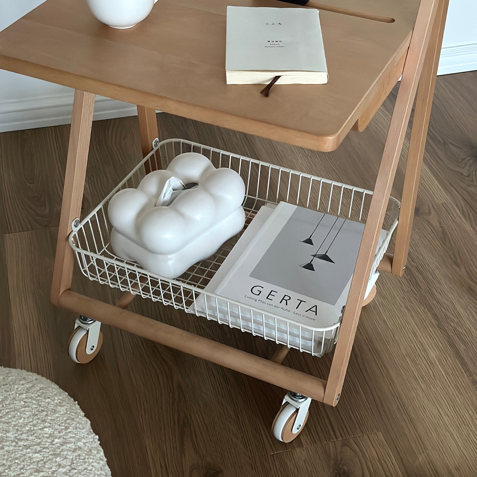 ナチュラルウッドのキャスター付きサイドテーブルの下の収納部分にティッシュケースと雑誌が置かれてある