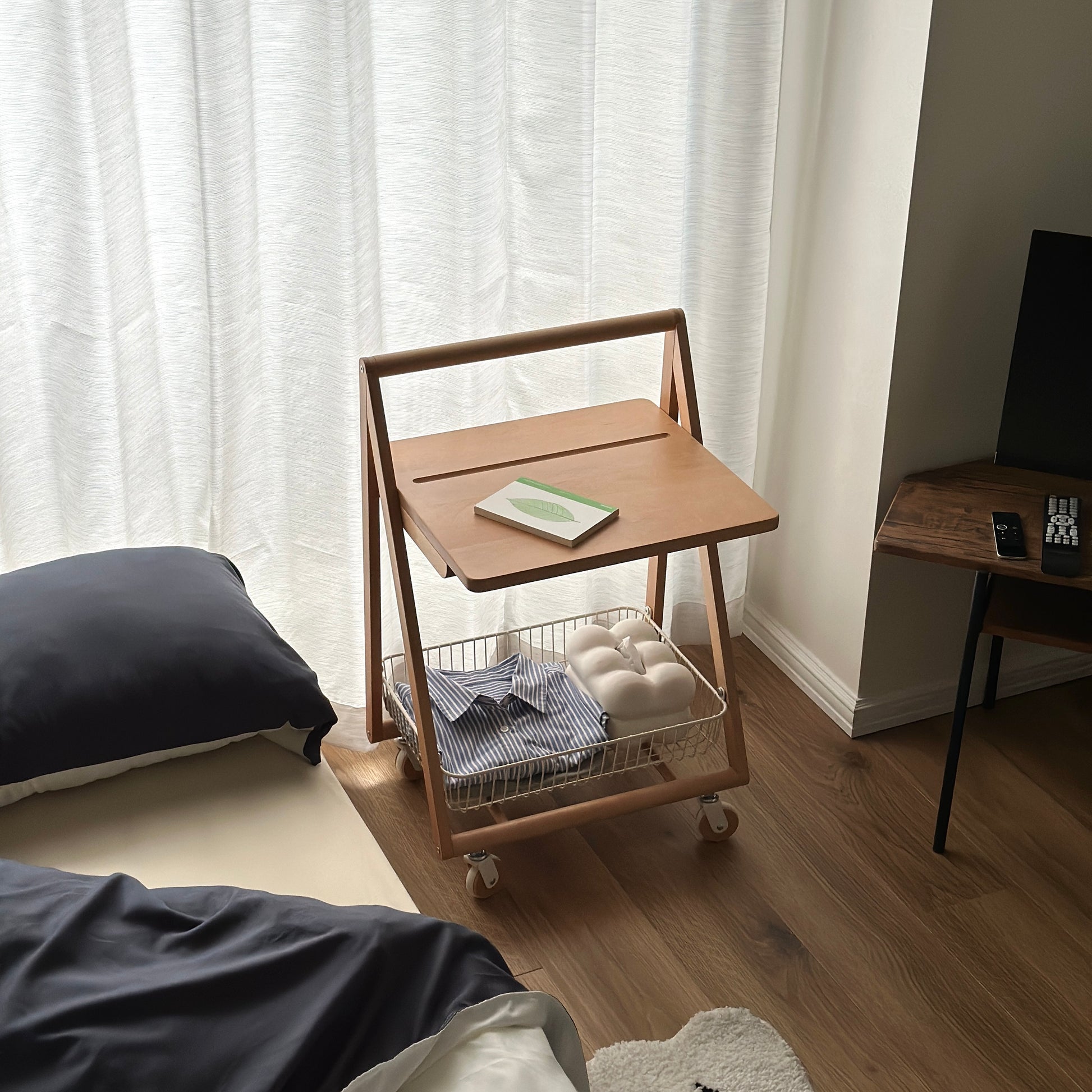 ナチュラルウッドのキャスター付きサイドテーブルをベッドサイドで使っている様子