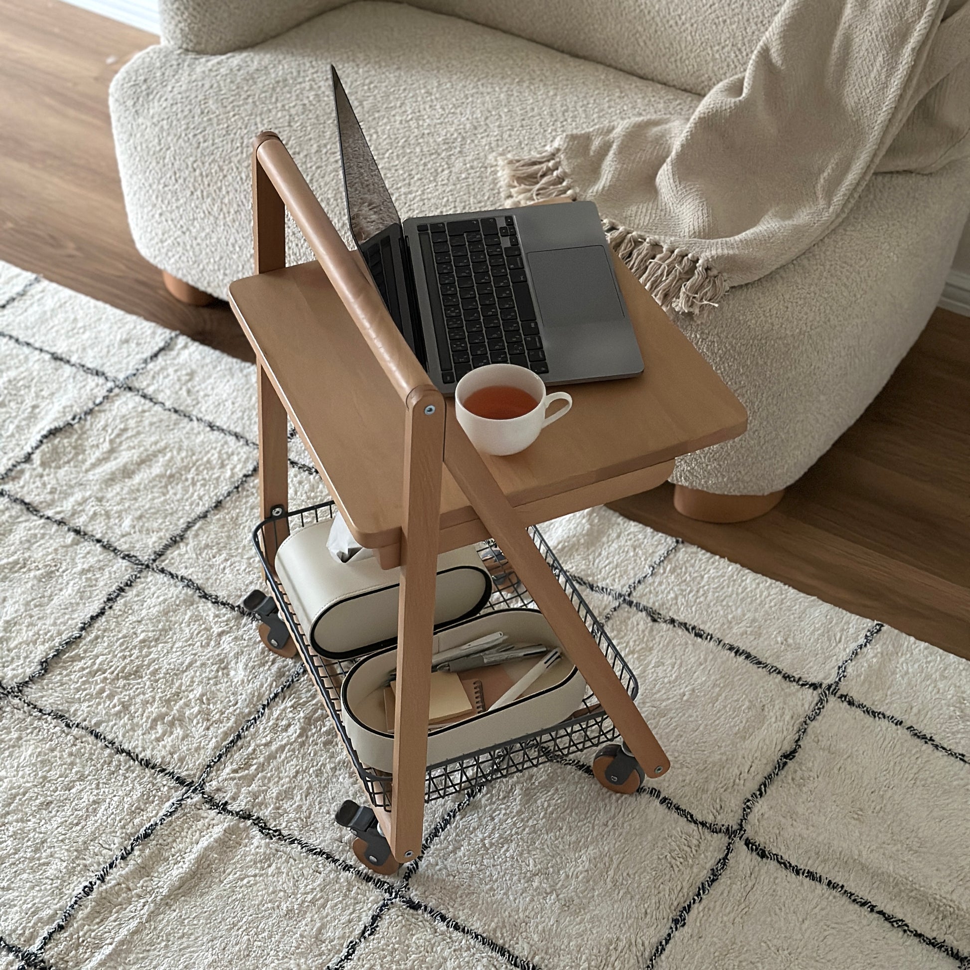 ナチュラルウッドのキャスター付きサイドテーブルにティーカップとパソコンが置かれてある