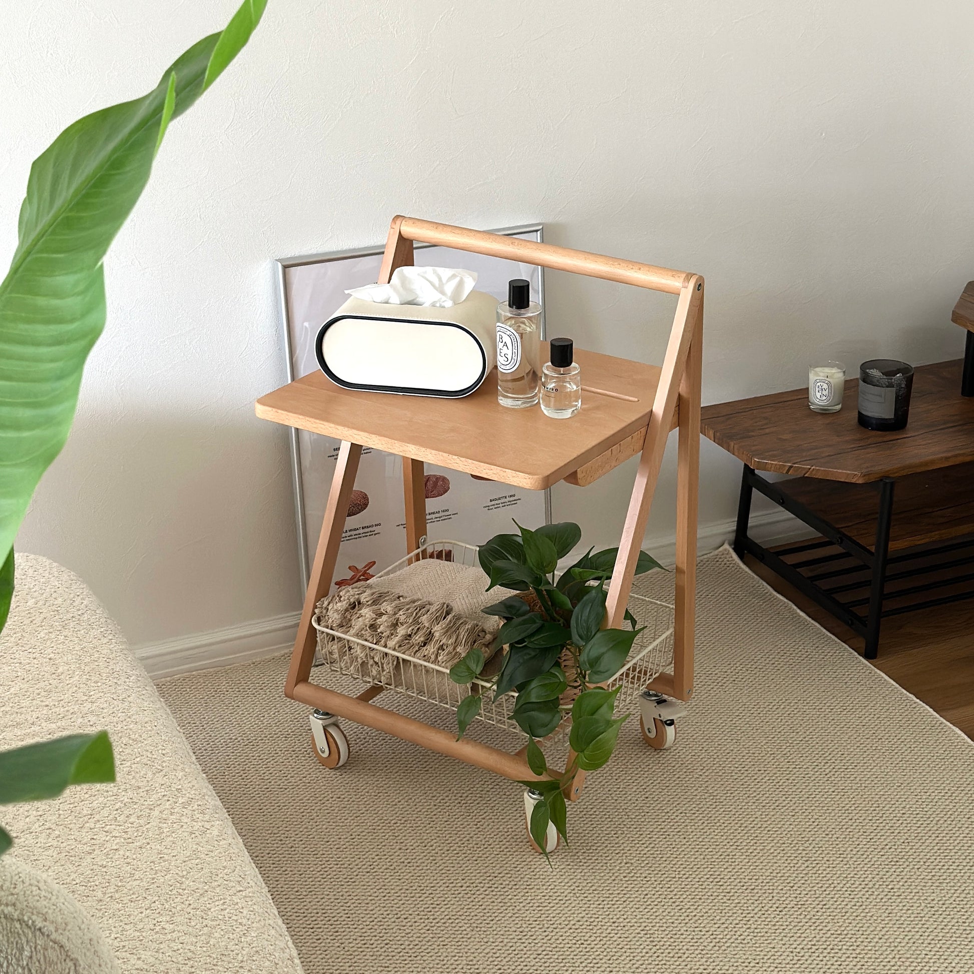 ナチュラルウッドのキャスター付きサイドテーブルの上にティッシュケースや香水、植物を置いている様子