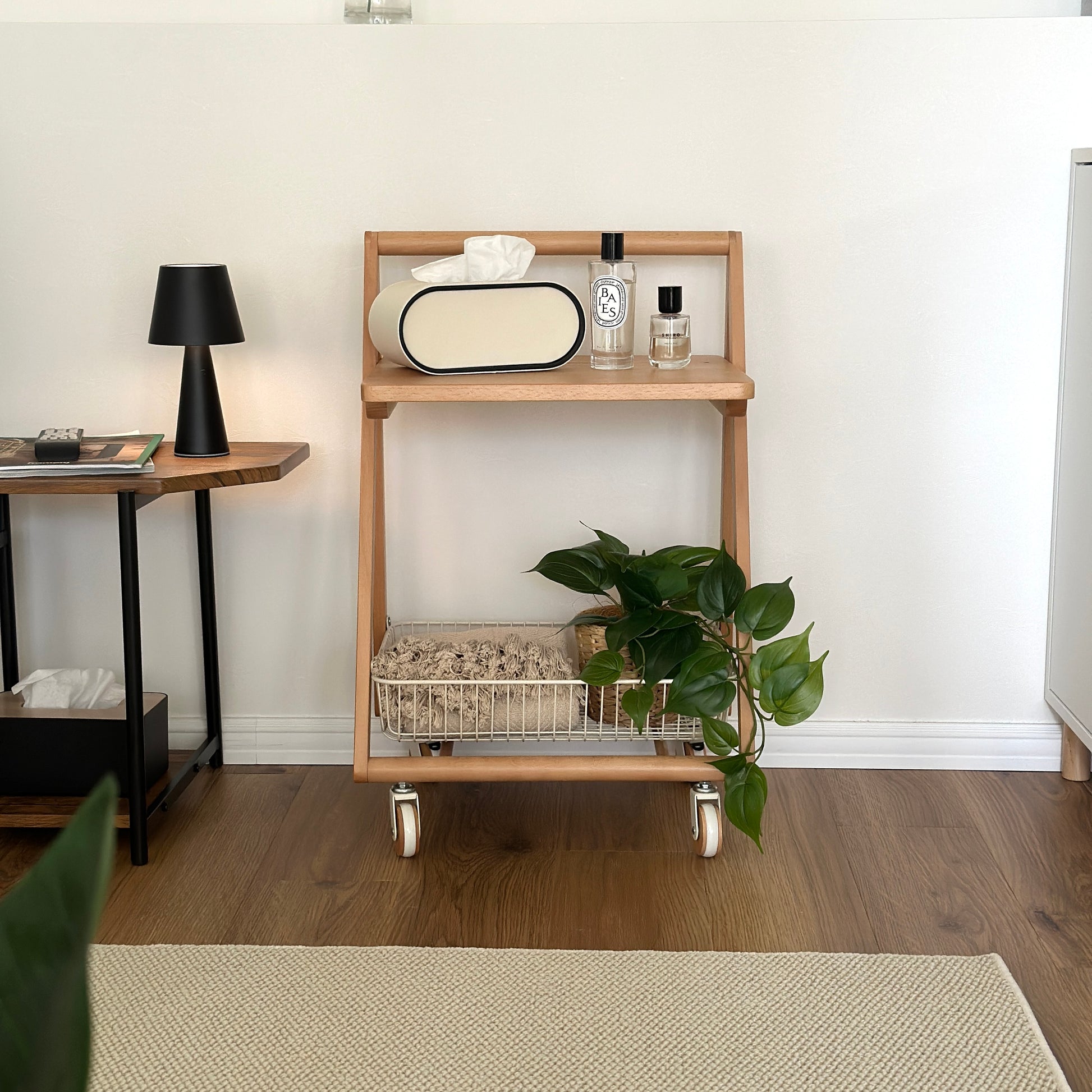 ナチュラルウッドのキャスター付きサイドテーブルにティッシュケースや香水、植物が置かれてある