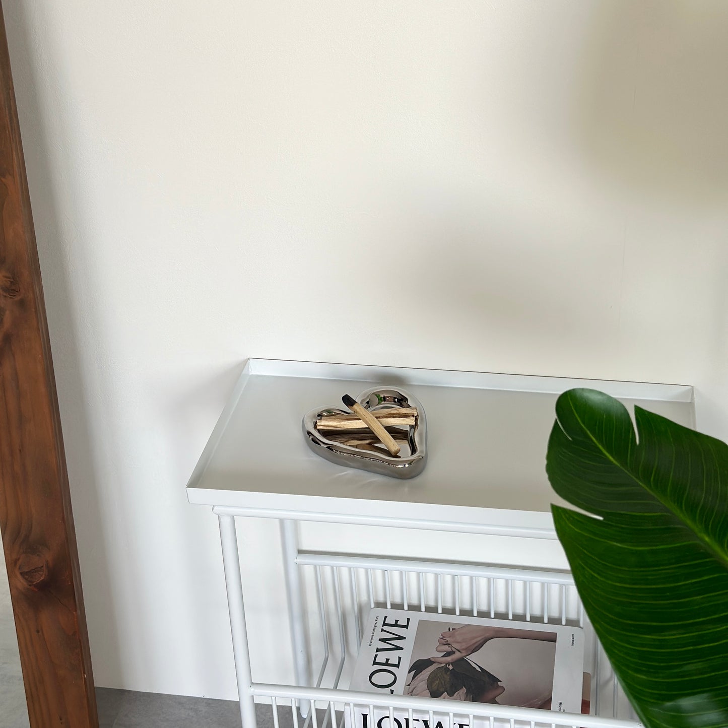 ホワイトのサイドテーブルの上に置いた縁があるシルバーのハート型のプレートにパロサントを乗せている様子