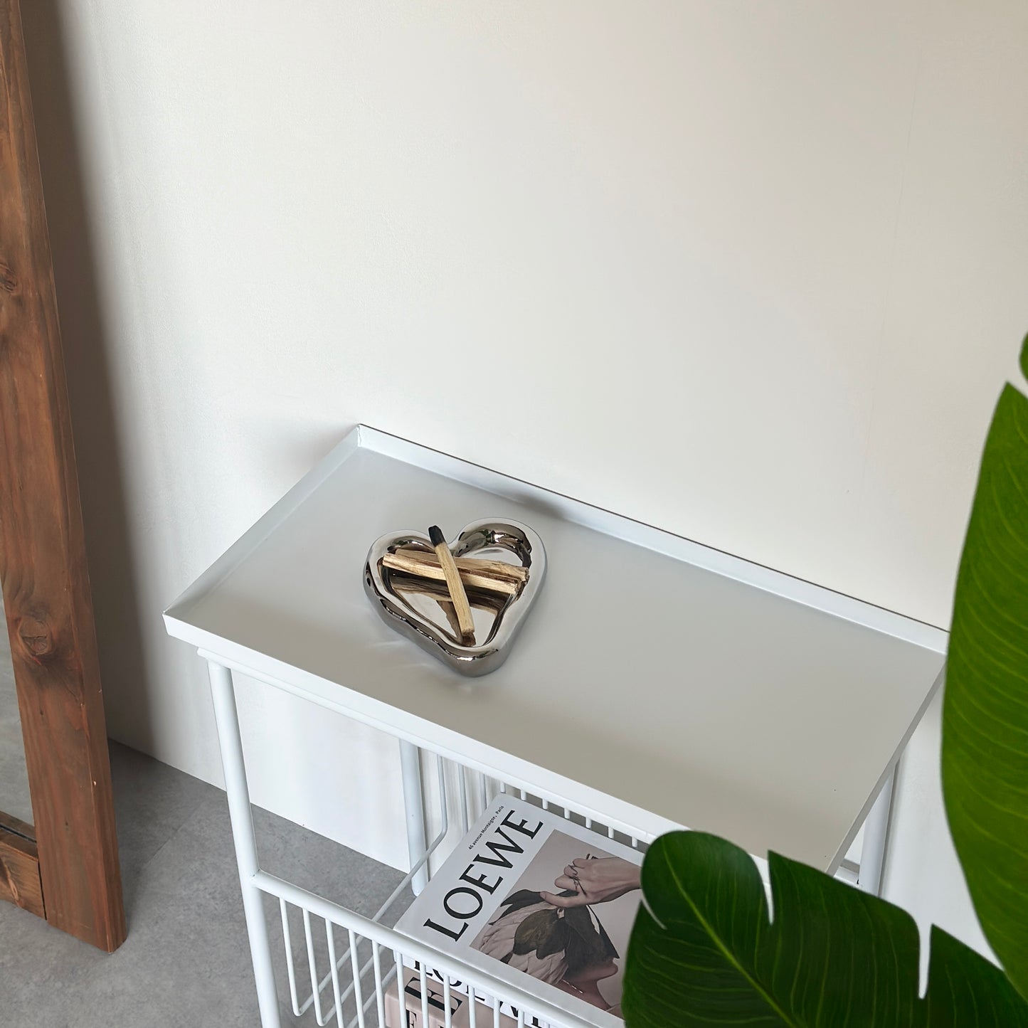 ホワイトのサイドテーブルの上乗っているハート型のシルバーのプレートにパロサントを置いている様子