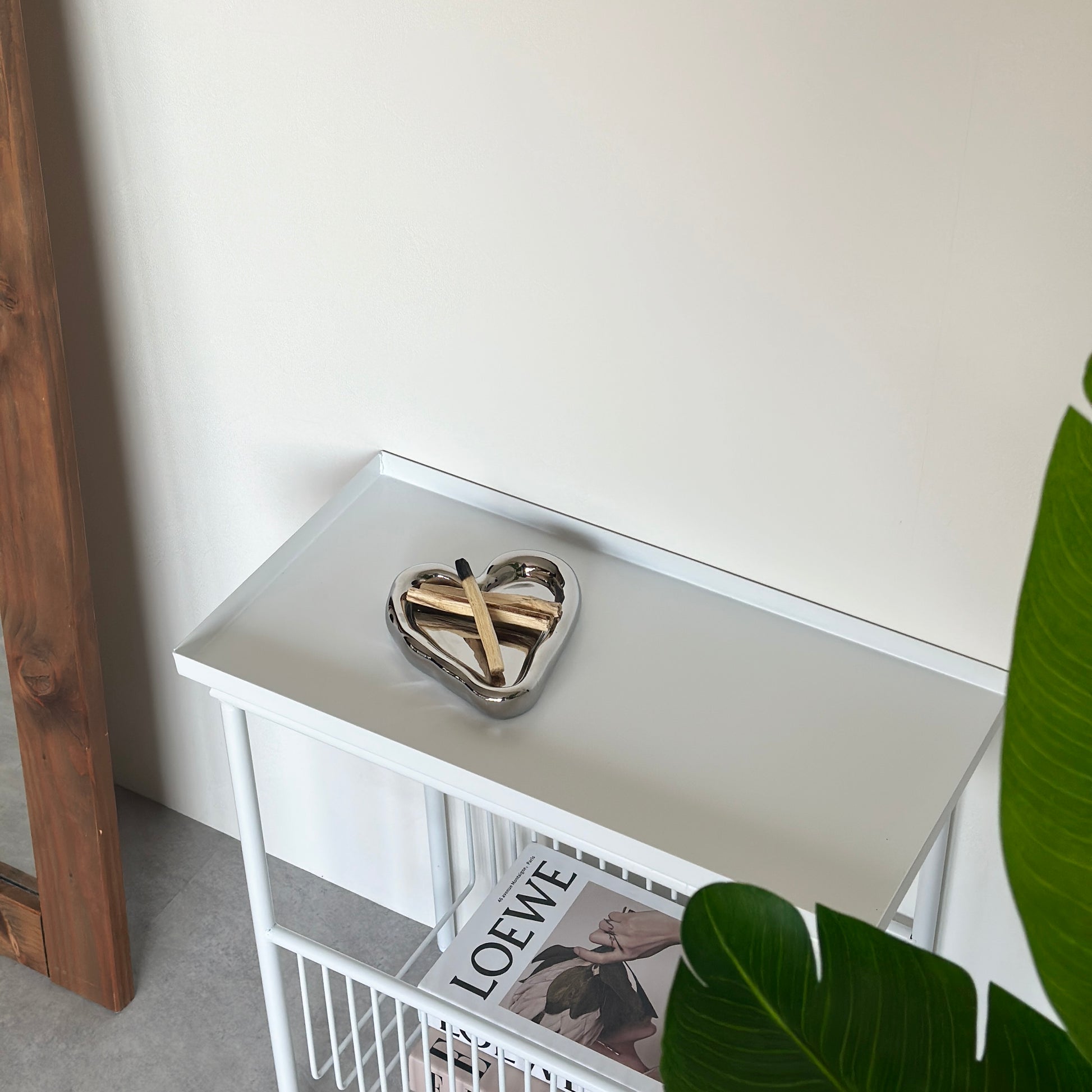 ホワイトのサイドテーブルの上乗っているハート型のシルバーのプレートにパロサントを置いている様子