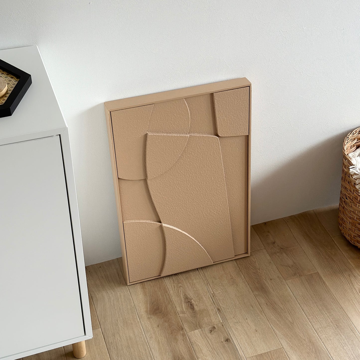 表面がベージュの立体的なアートが壁に立てかけられている