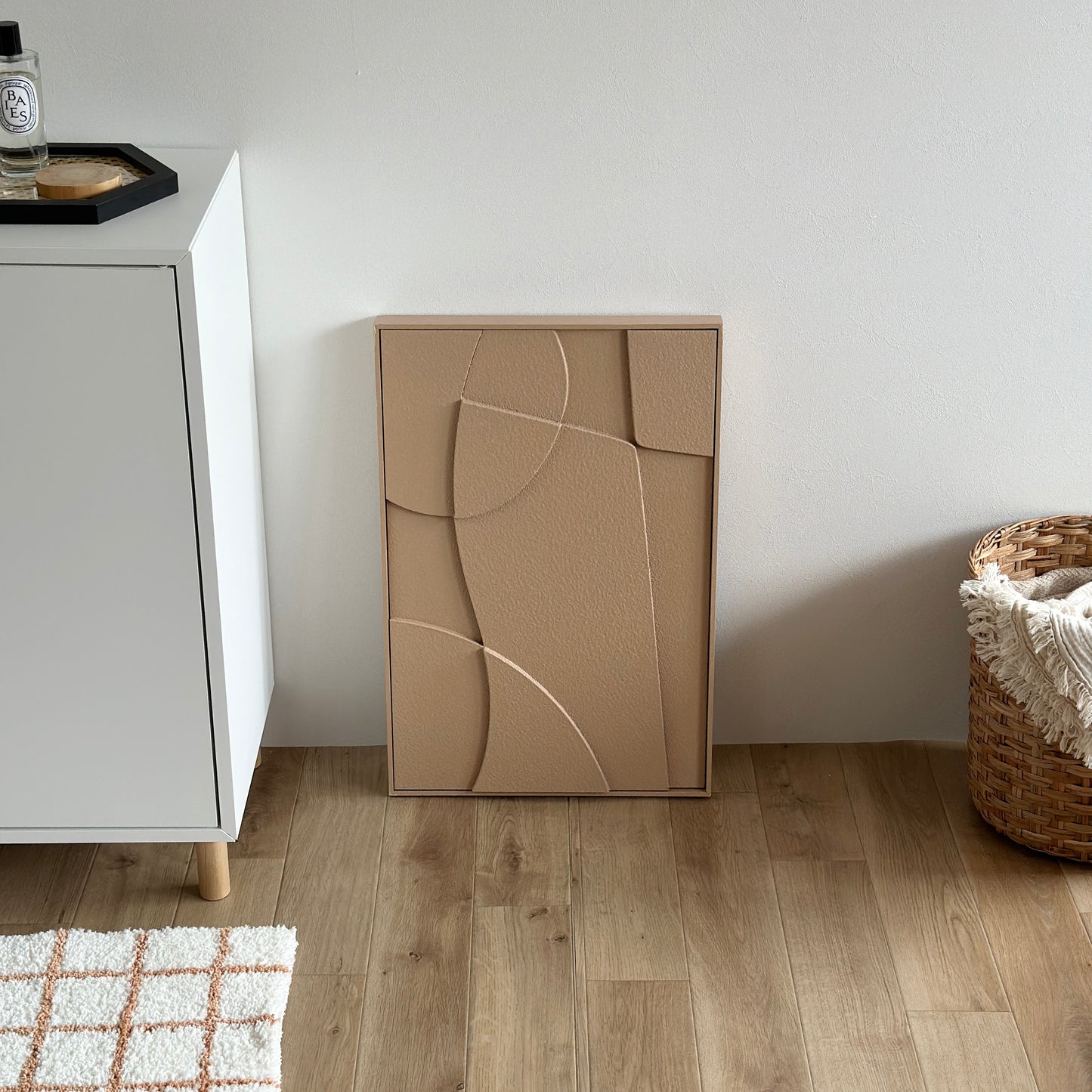 表面がベージュの立体的なアートが壁に立てかけられている