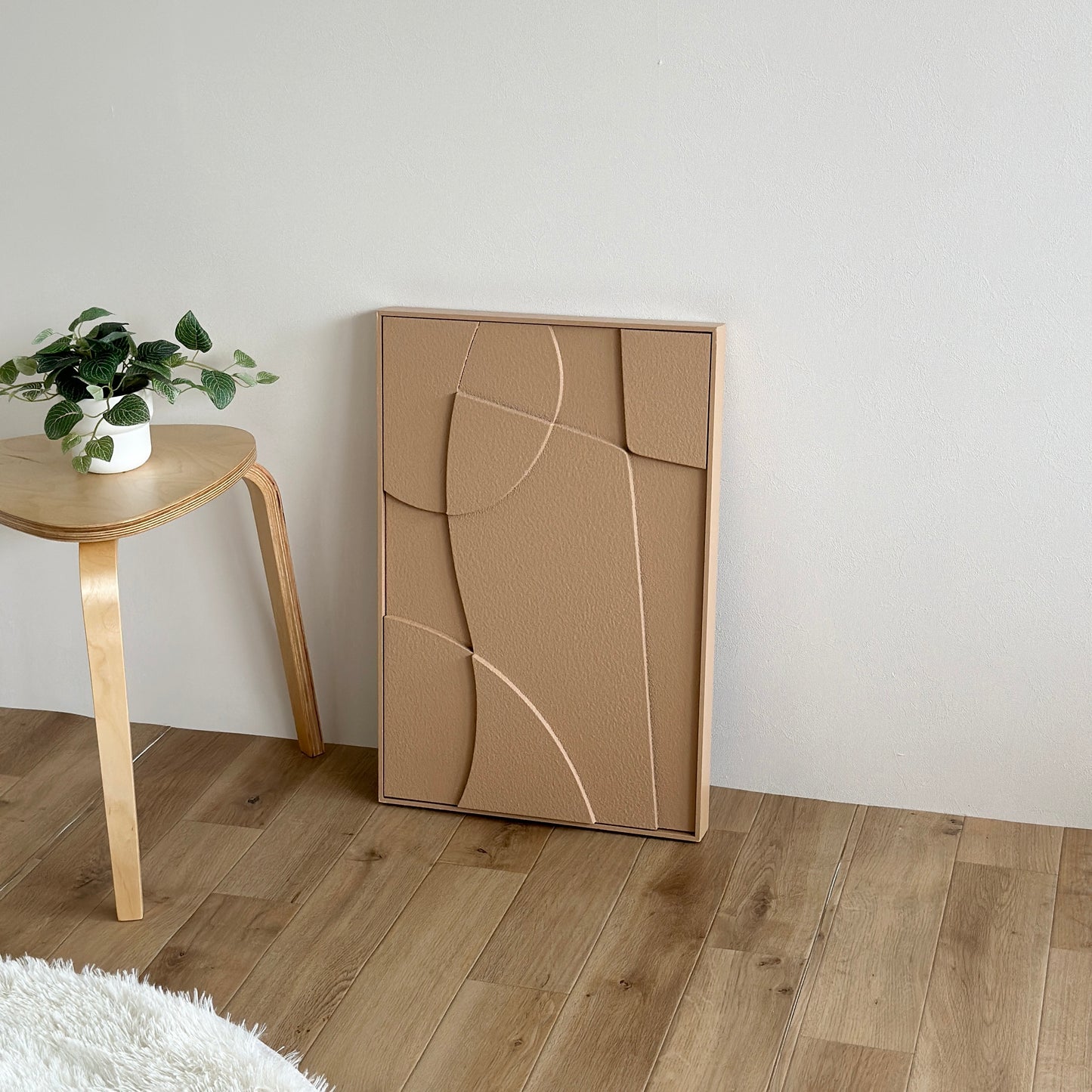 表面がベージュの立体的なアートが壁に立てかけられている