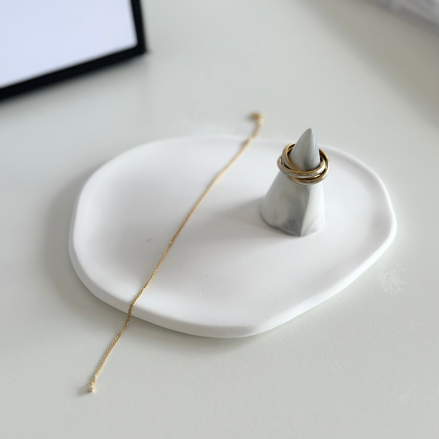 石膏素材の白いプレートの上にアクセサリーが乗せられている