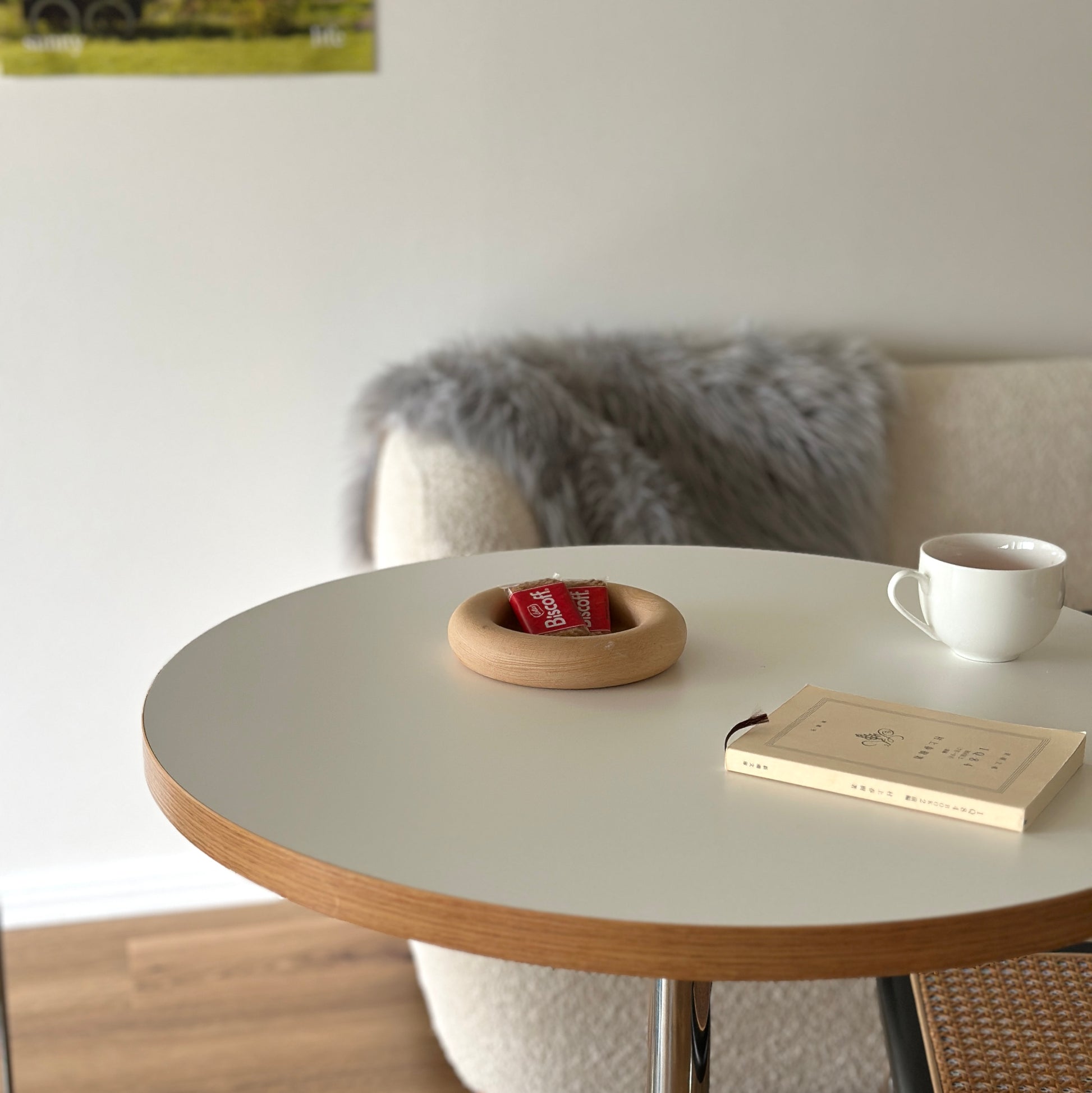 白い丸のテーブルの上にお菓子がのったフチがぽってりとした木のプレートが置かれてある。