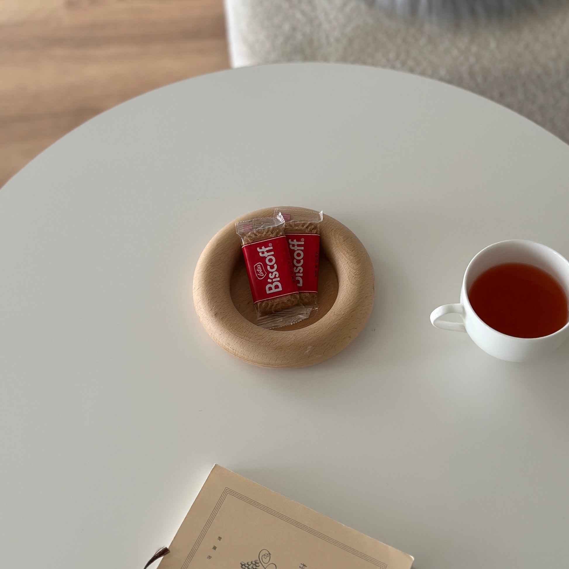 白い丸のテーブルの上にお菓子がのったフチがぽってりとした木のプレートが置かれてある。