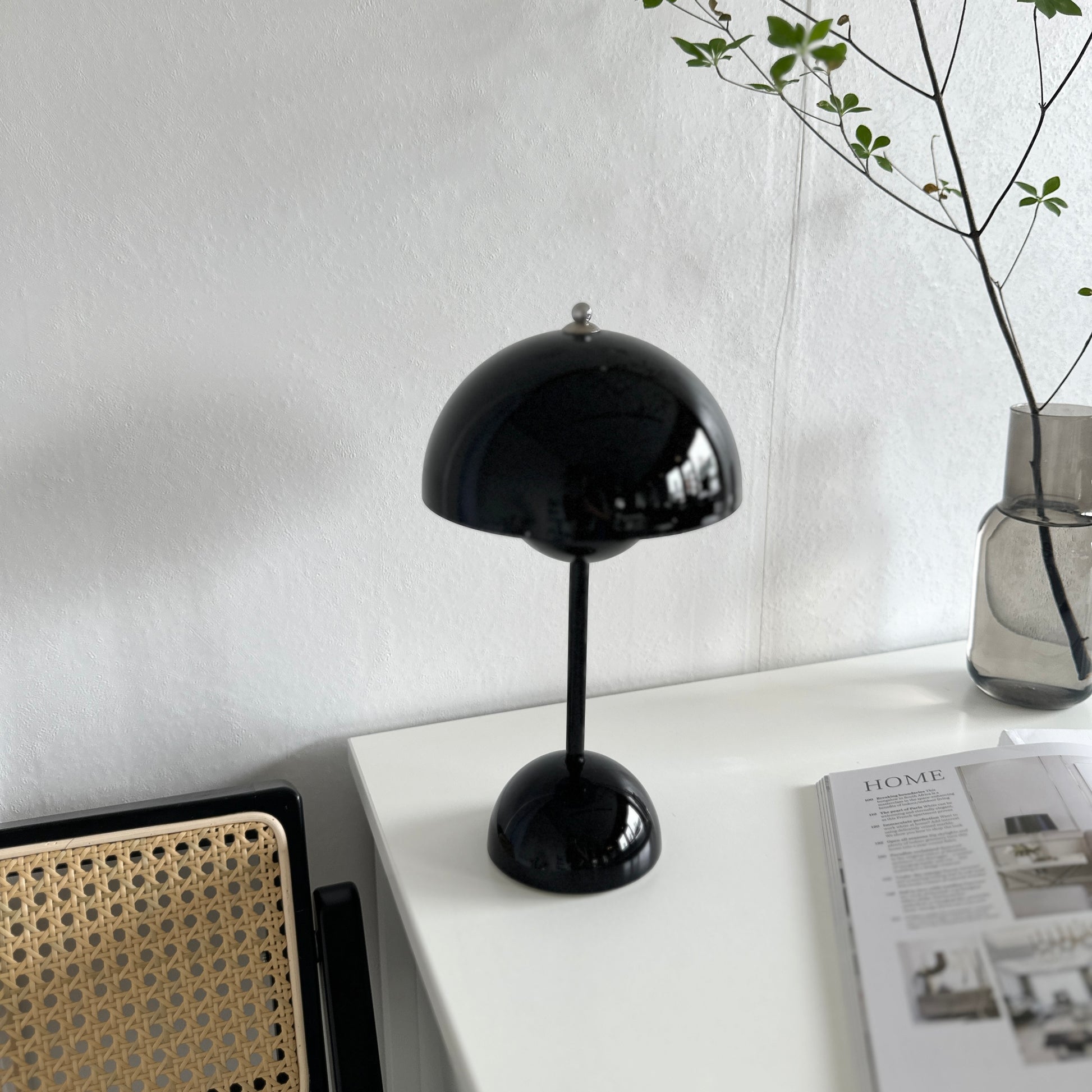 ブラックの丸傘のテーブルライトが棚の上に置いてあり、横に植物が飾ってある