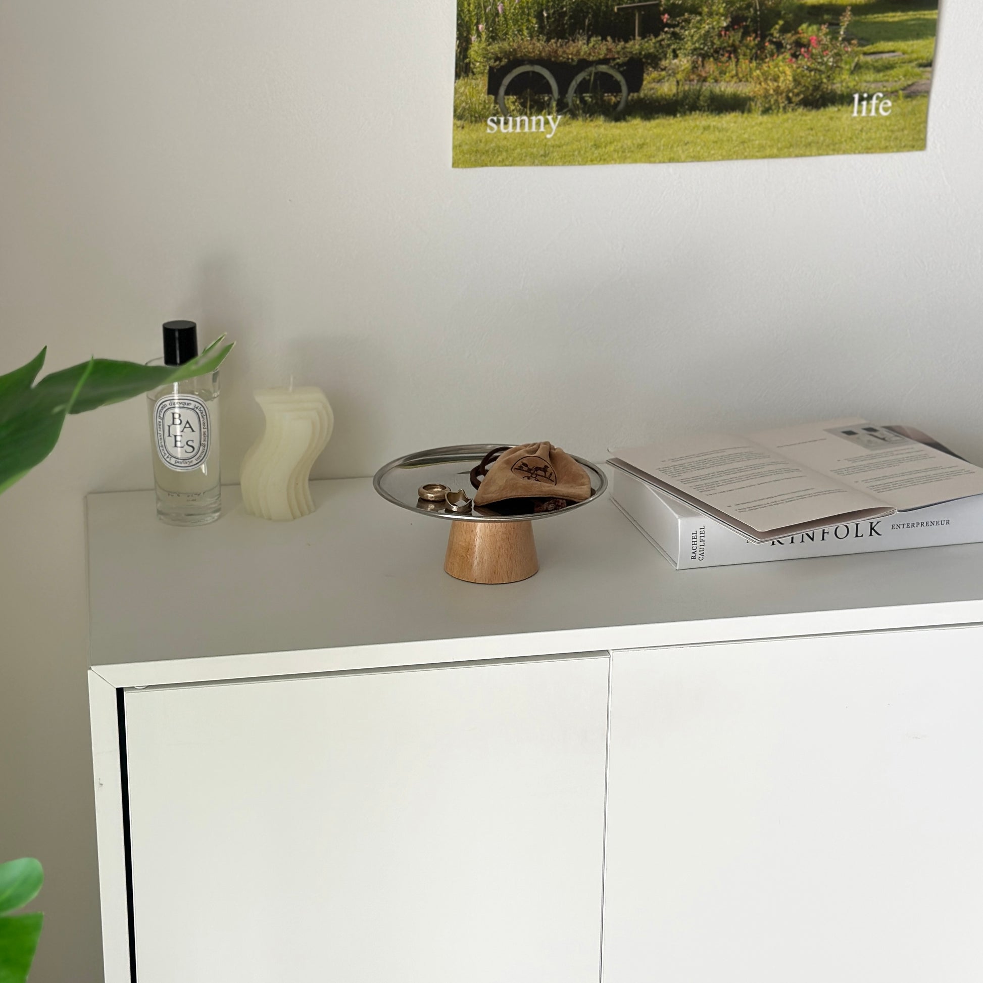 白い棚の上に木製の脚とステンレス素材の丸いトレイが置かれてある。