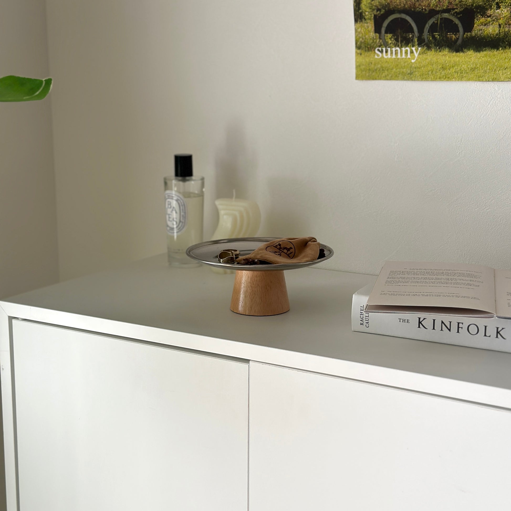 白い棚の上に木製の脚とステンレス素材の丸いトレイが置かれてある。