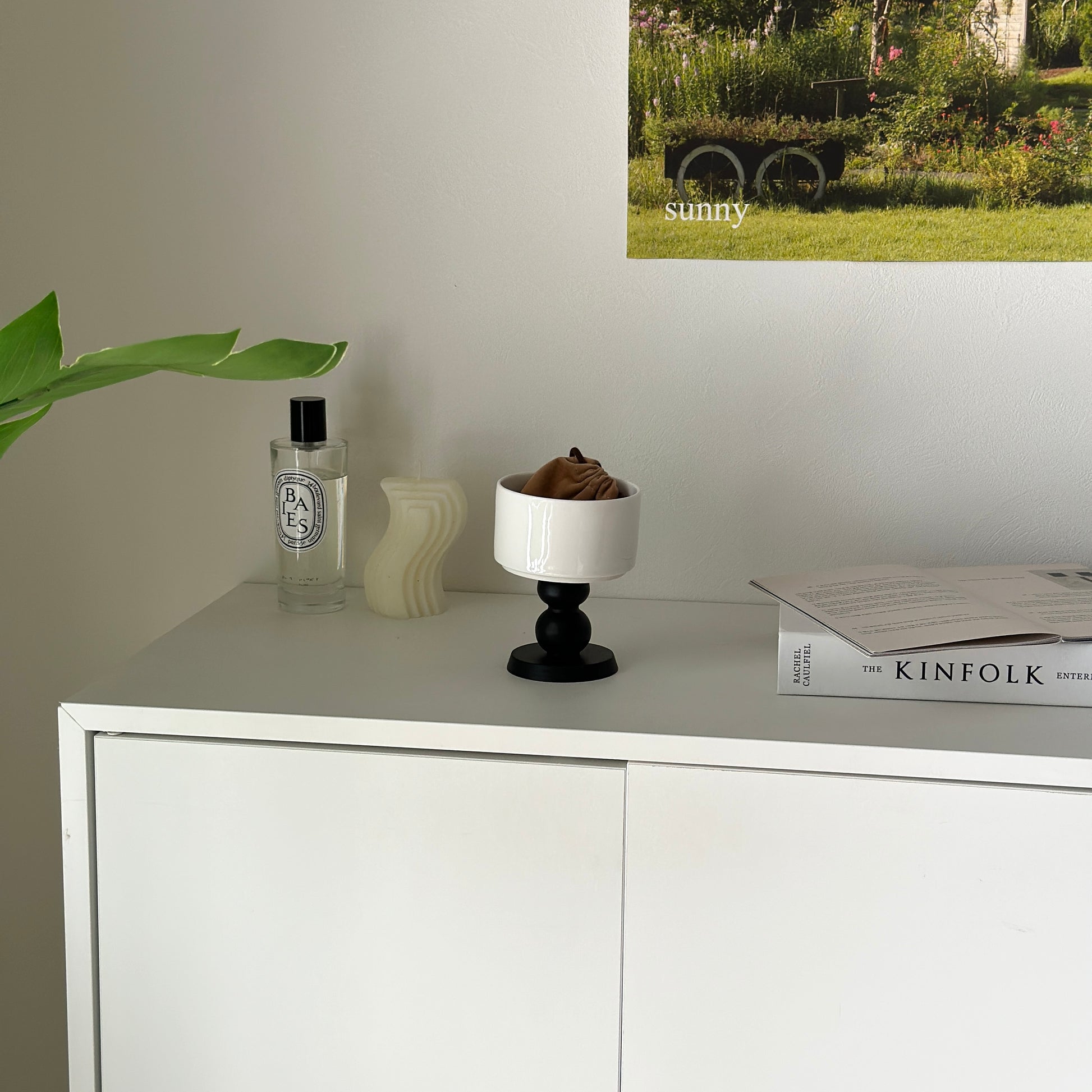 白の棚の上に陶器の器に黒いウッド脚が付いたボウルが置かれてある。