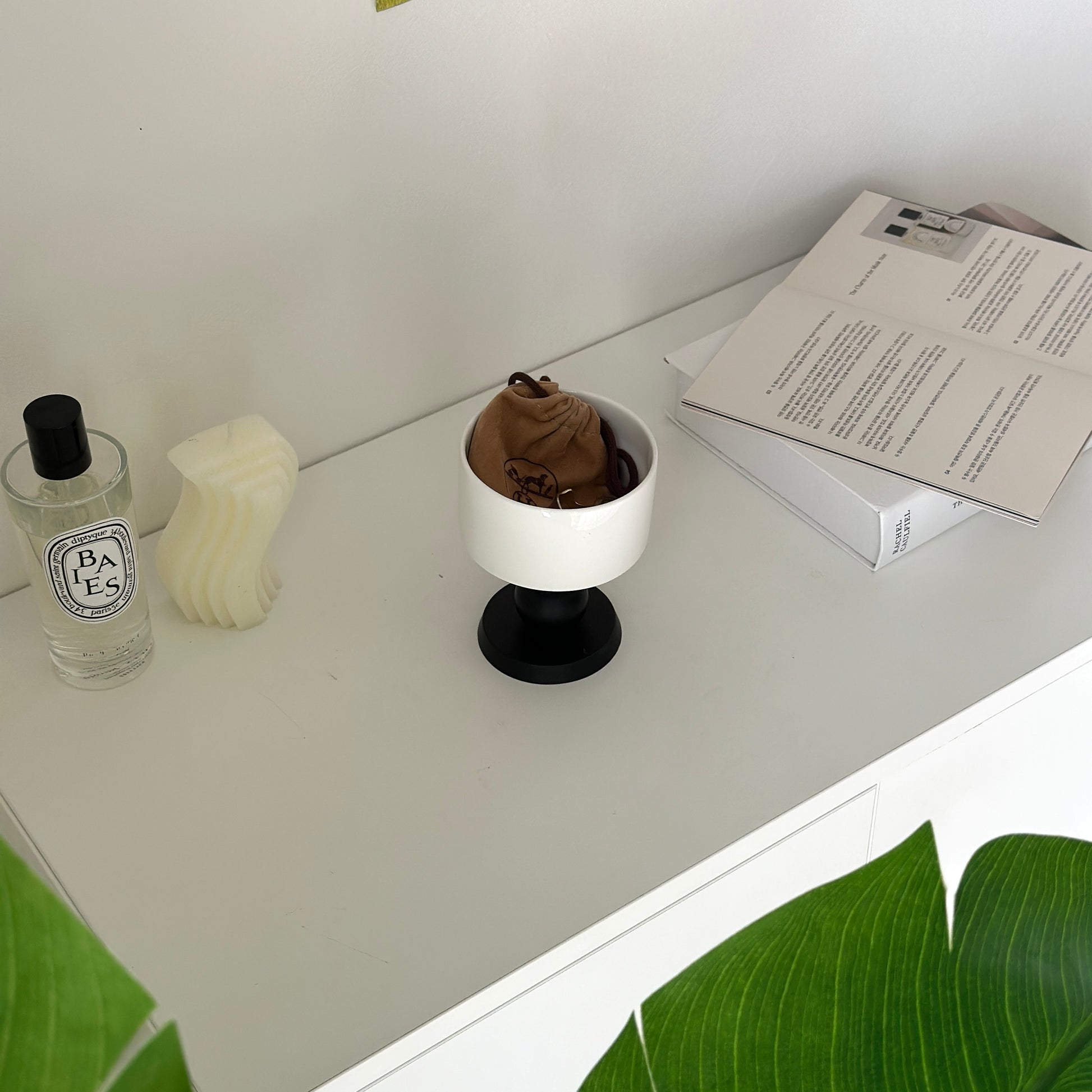 白の棚の上に陶器の器に黒いウッド脚が付いたボウルが置かれてある。