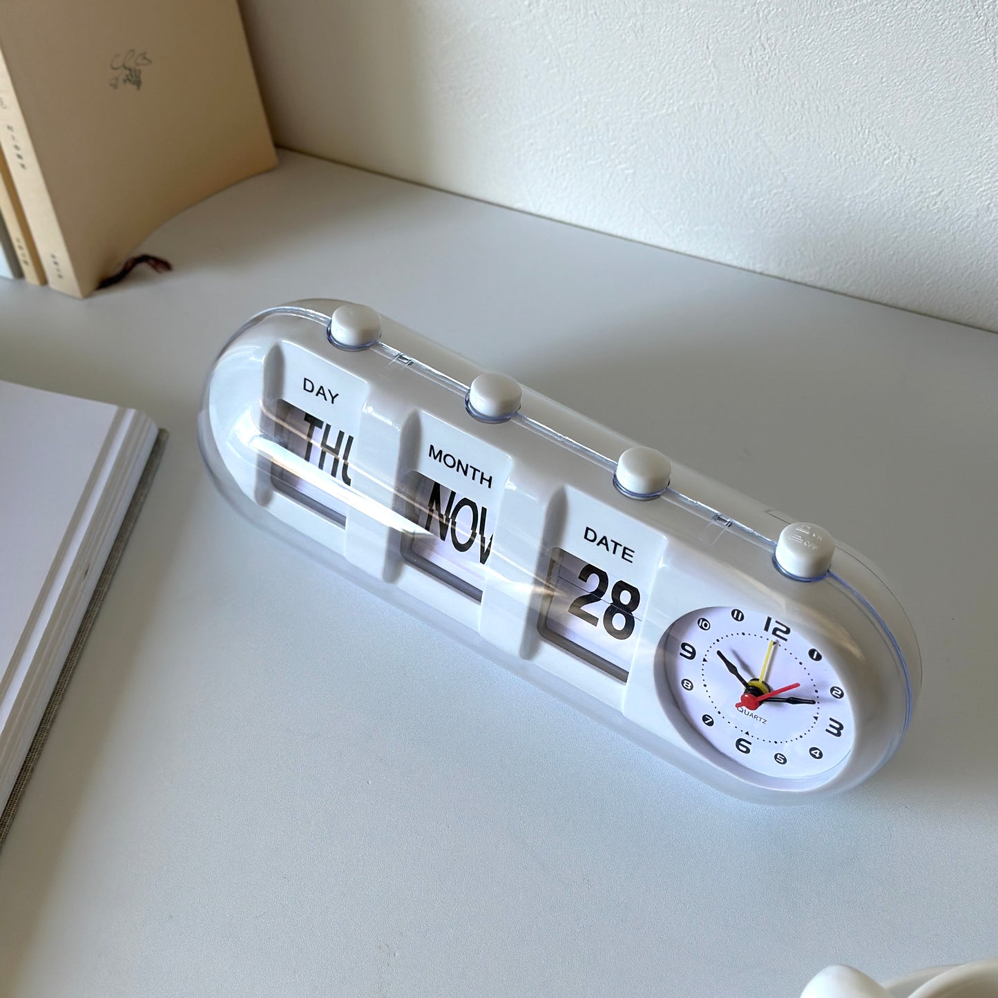 ボタンを押してペラペラ変えることができる白のカレンダー付き時計