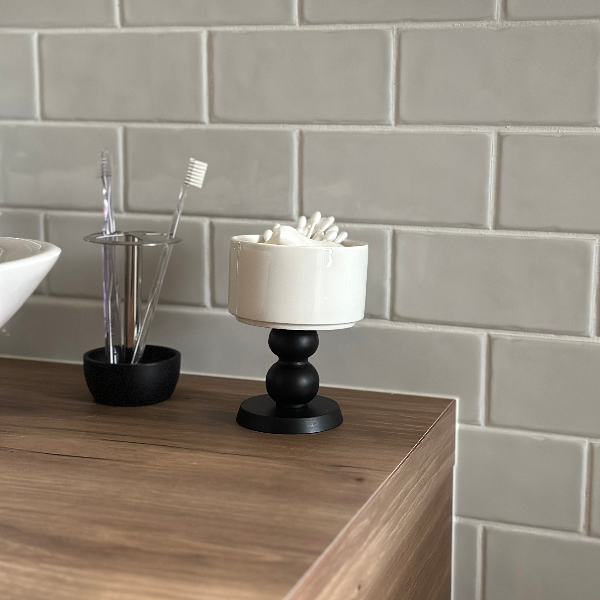 茶色い棚の上に陶器の器にウッド脚が付いたボウルが置かれてある。