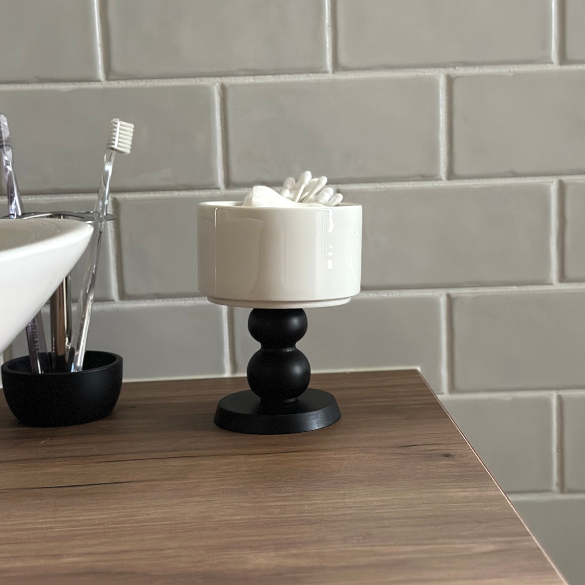 茶色い棚の上に陶器の器に黒いウッド脚が付いたボウルが置かれてある。