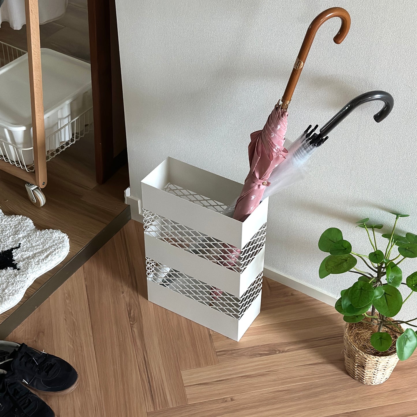 白メッシュのスチール素材の傘立てにピンクの傘とビニール傘が入ってある様子