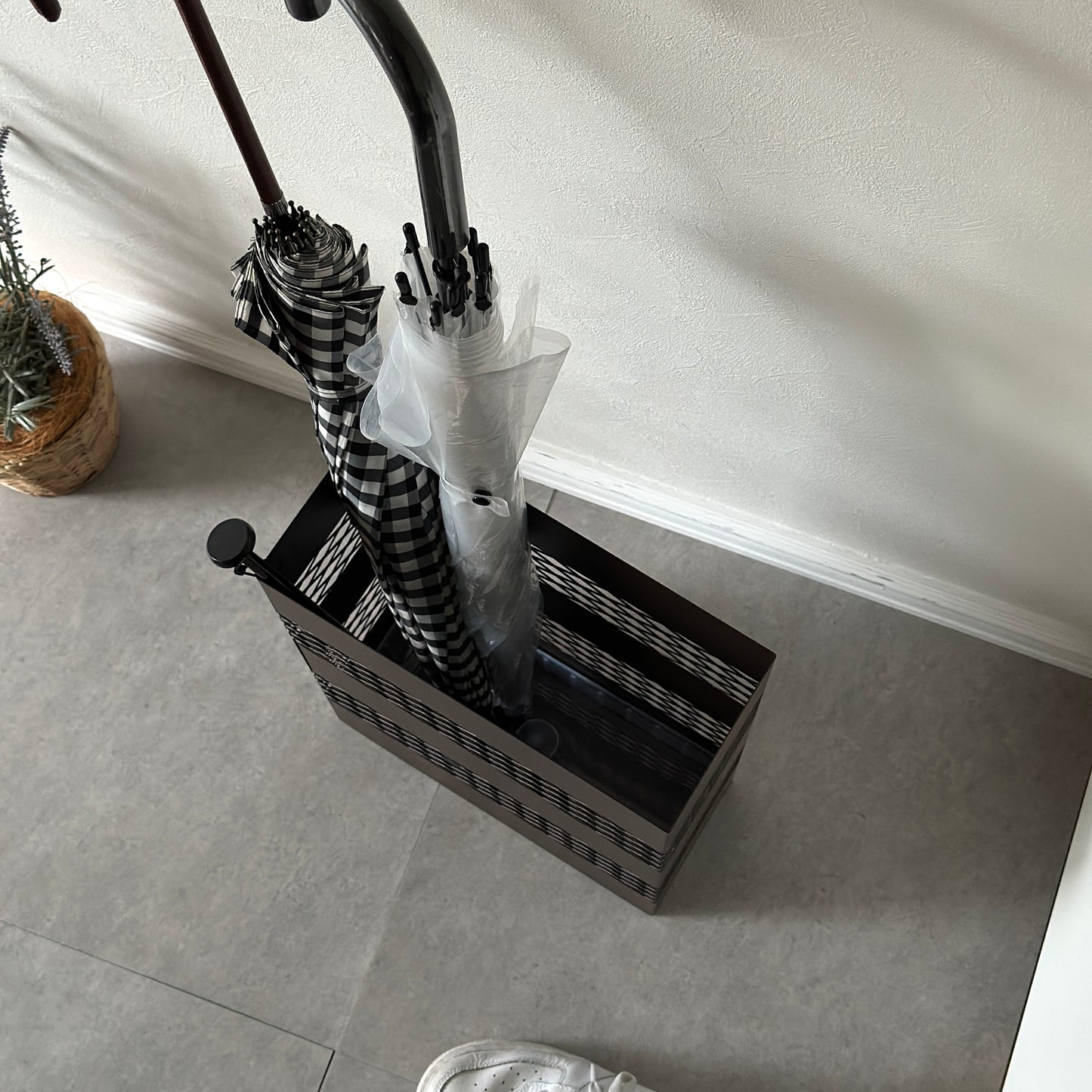 黒メッシュのスチール素材の傘立てにチェックの傘とビニール傘が入ってあるところを上から撮った様子