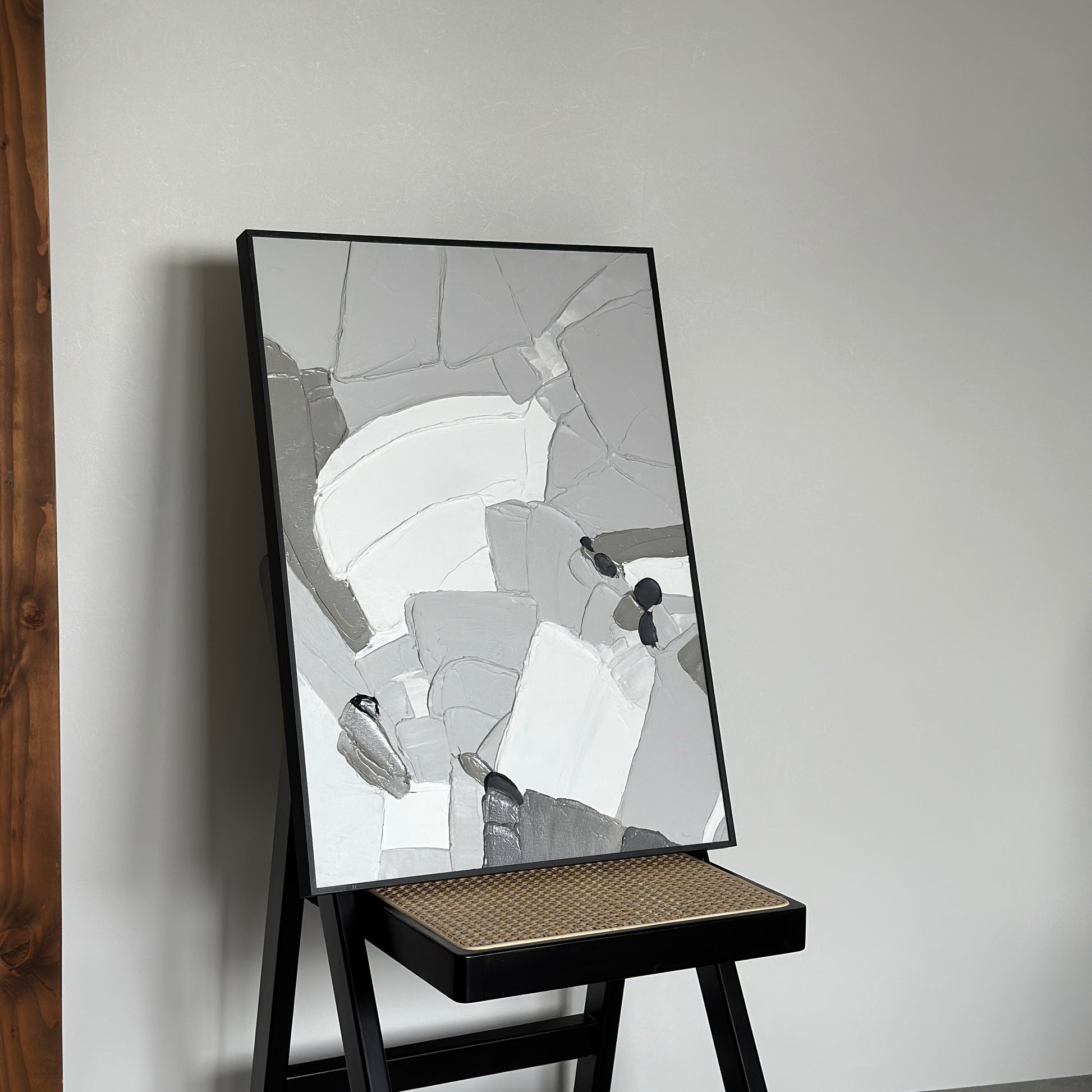 椅子の上に乗せられた表面に凹凸があるモノトーンカラーのアート