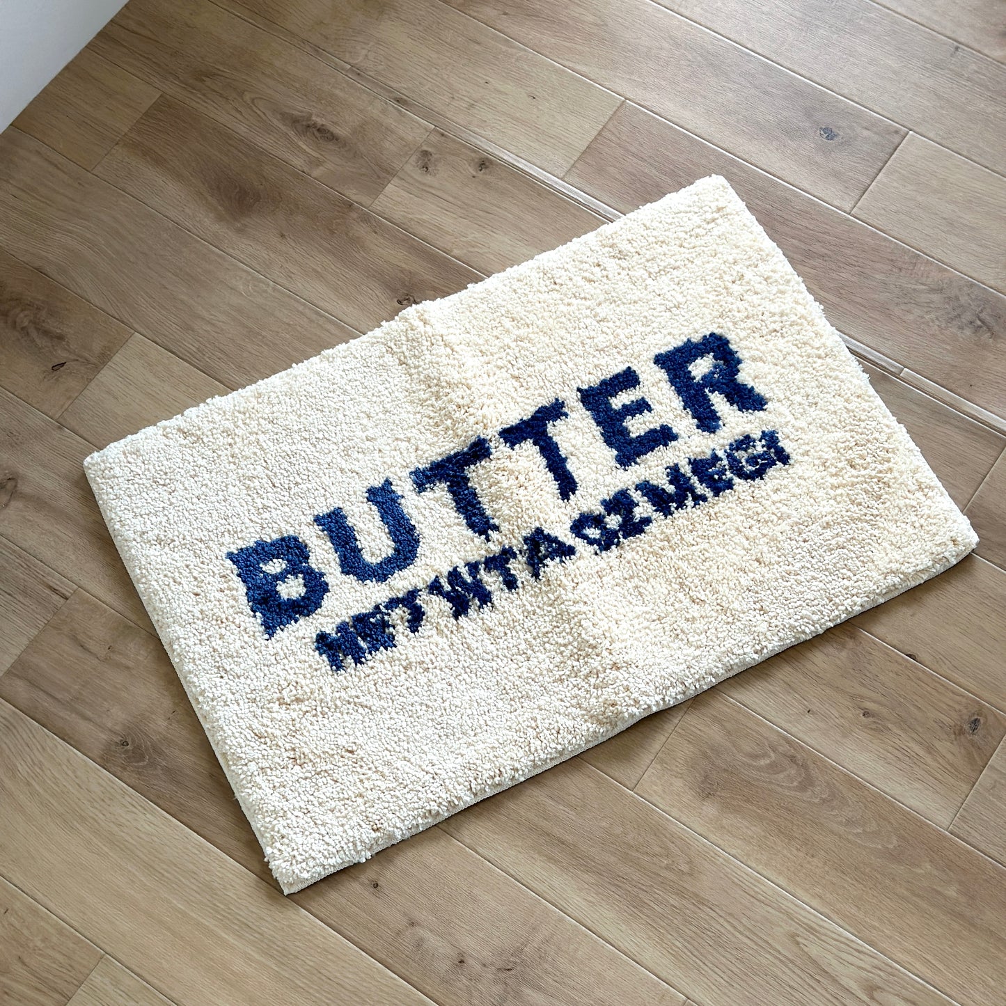 白地に青文字で”BUTTER”の文字が描かれたミニラグ