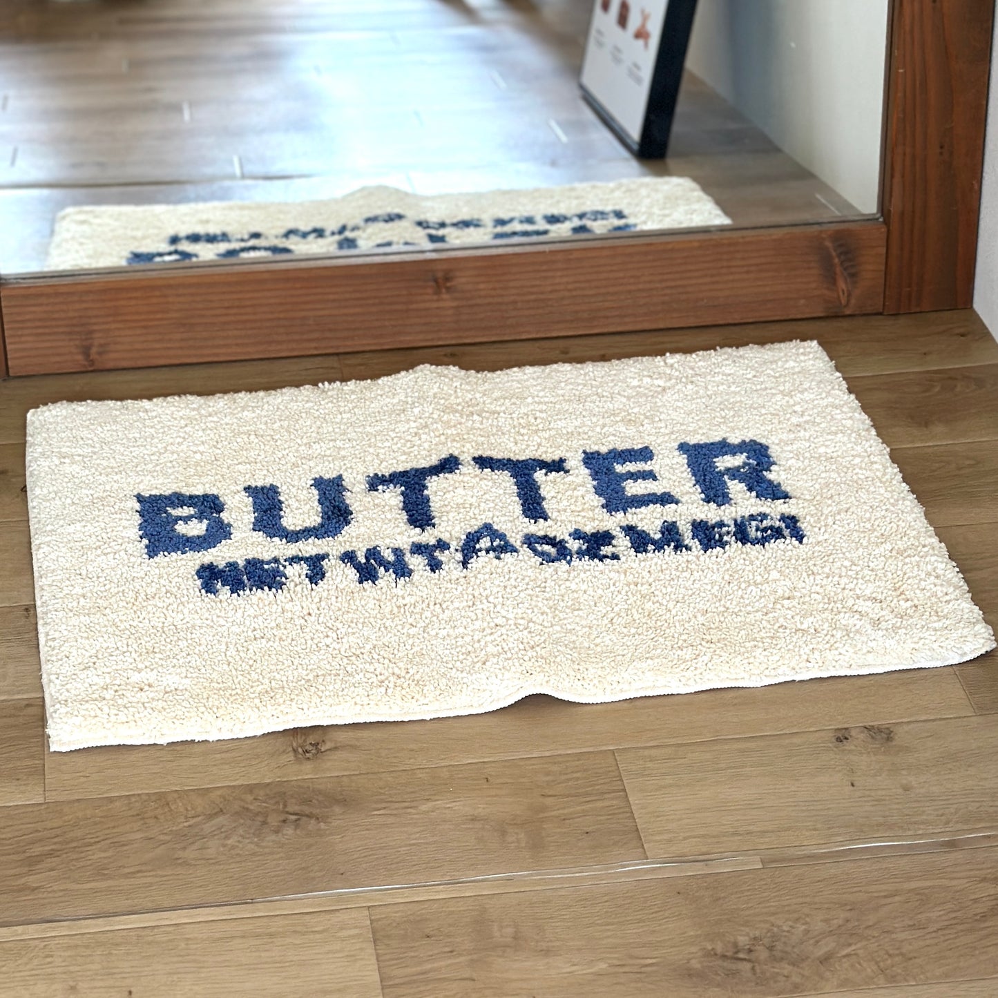 姿見の前に敷かれた白地に青文字で”BUTTER”の文字が描かれたミニラグ