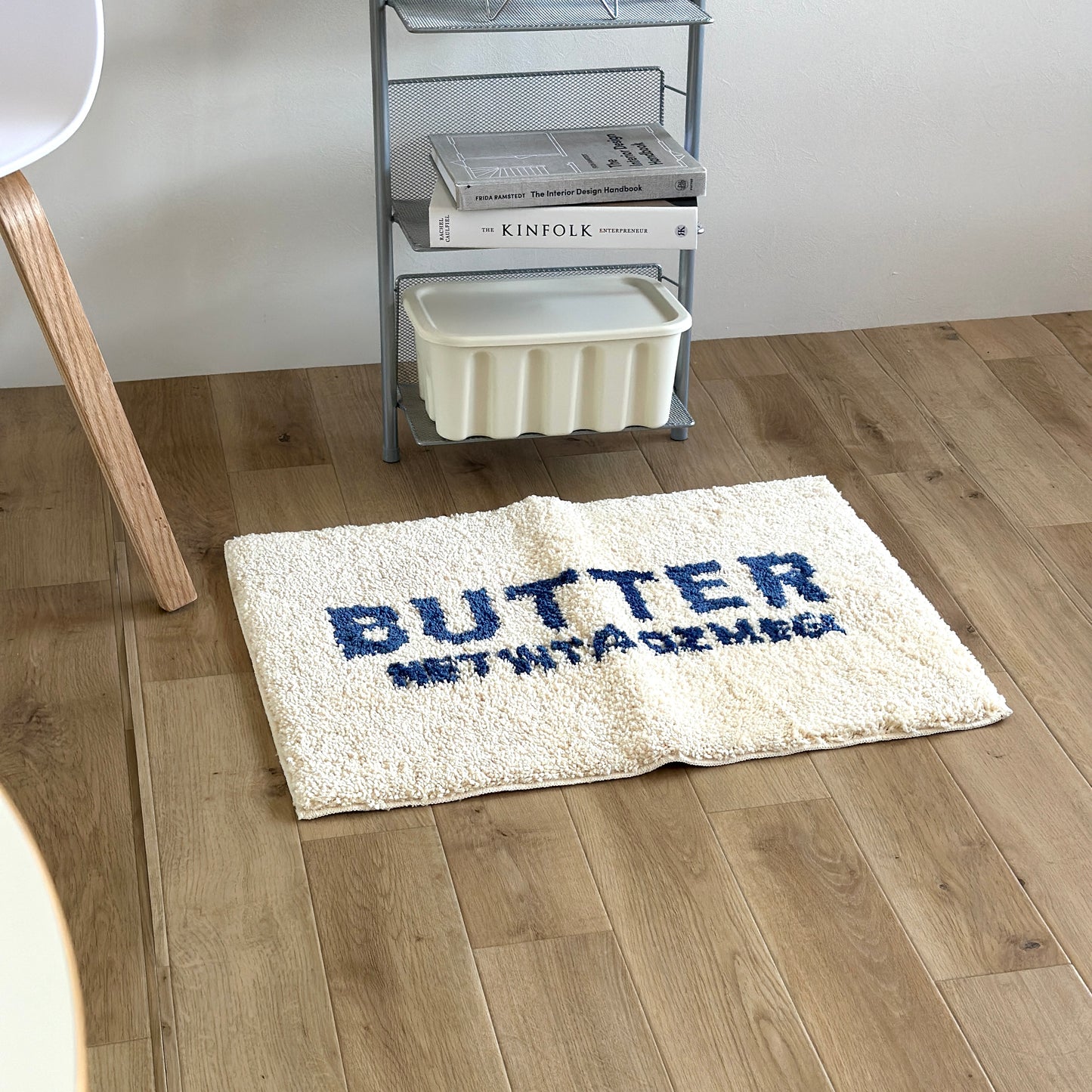 シェルフの前に置かれた白地に青文字で”BUTTER”の文字が描かれたミニラグ