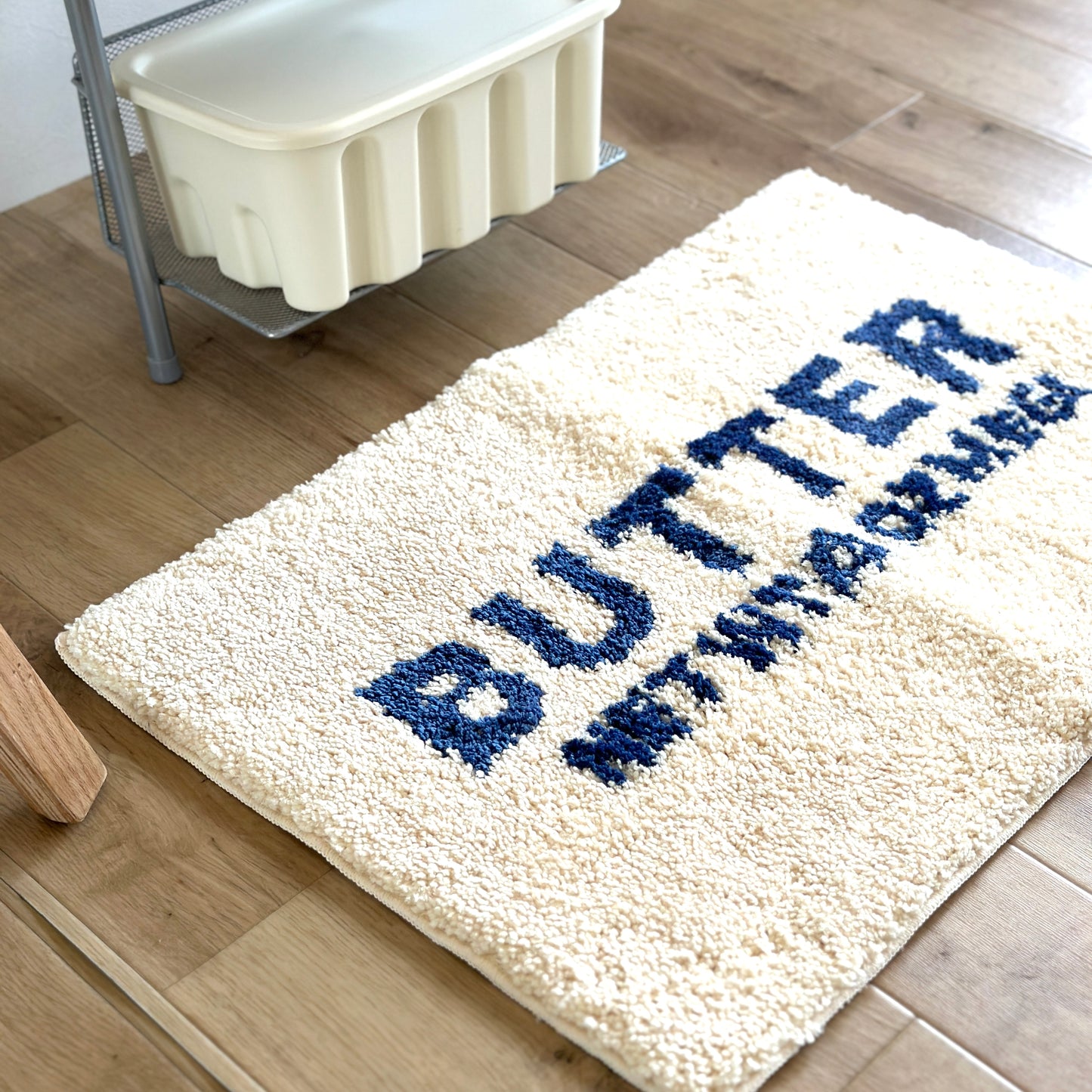 白地に青文字で”BUTTER”の文字が描かれたミニラグ
