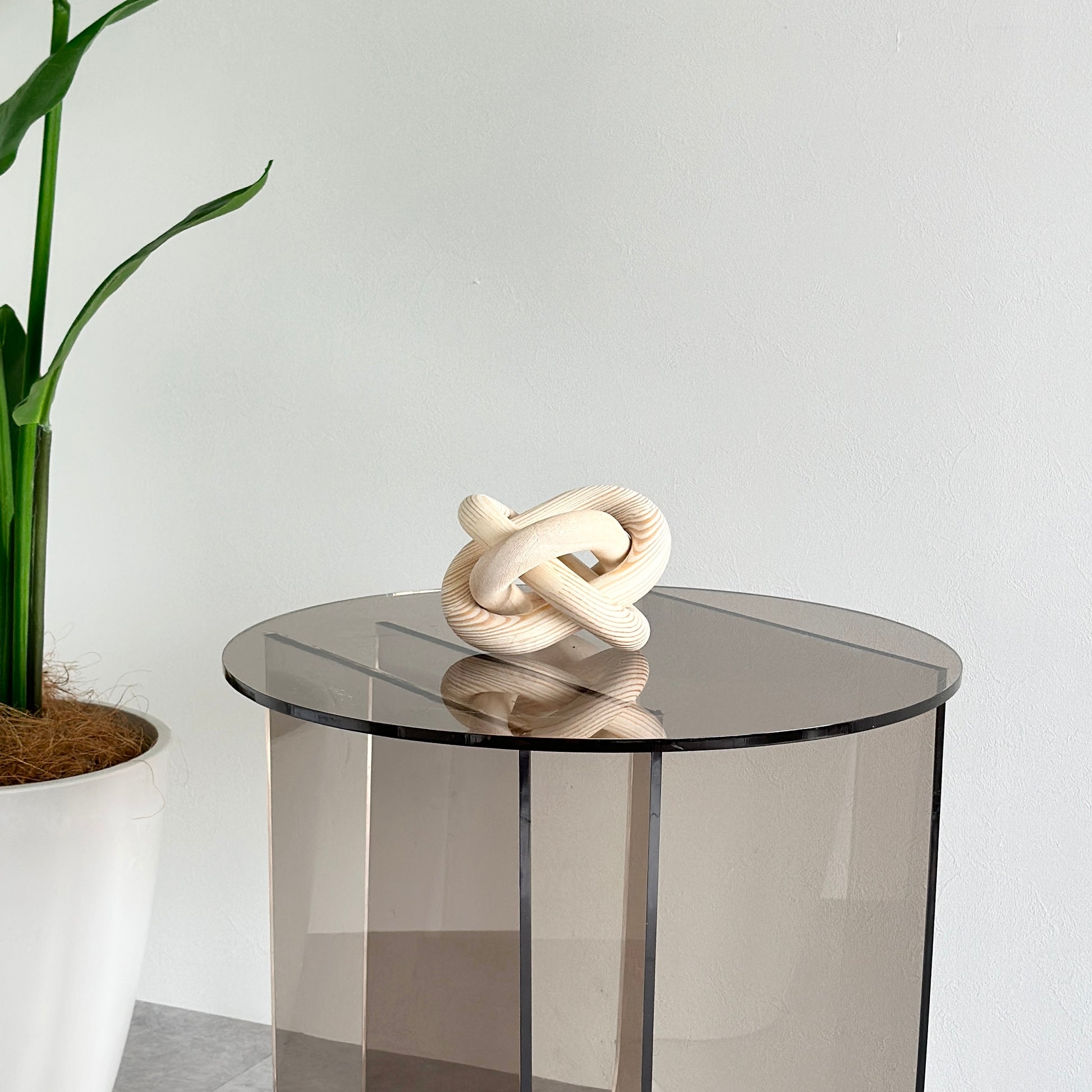 グレーのクリアテーブルの上に置かれた木製のオブジェ