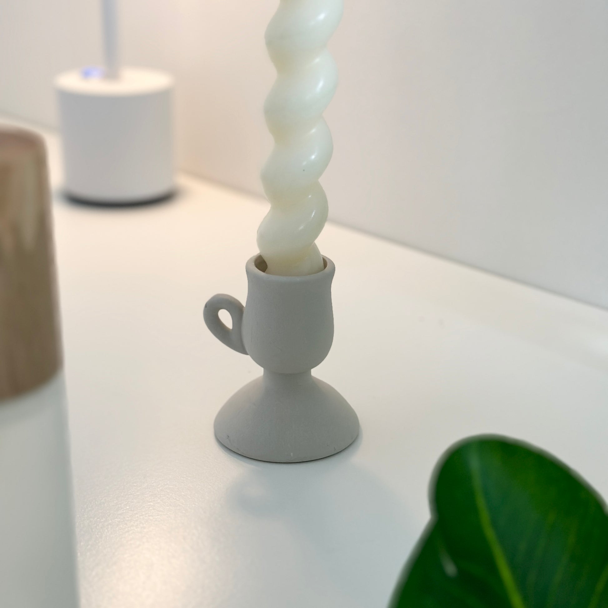 マッドホワイトのキャンドルホルダーにキャンドルがセットされている