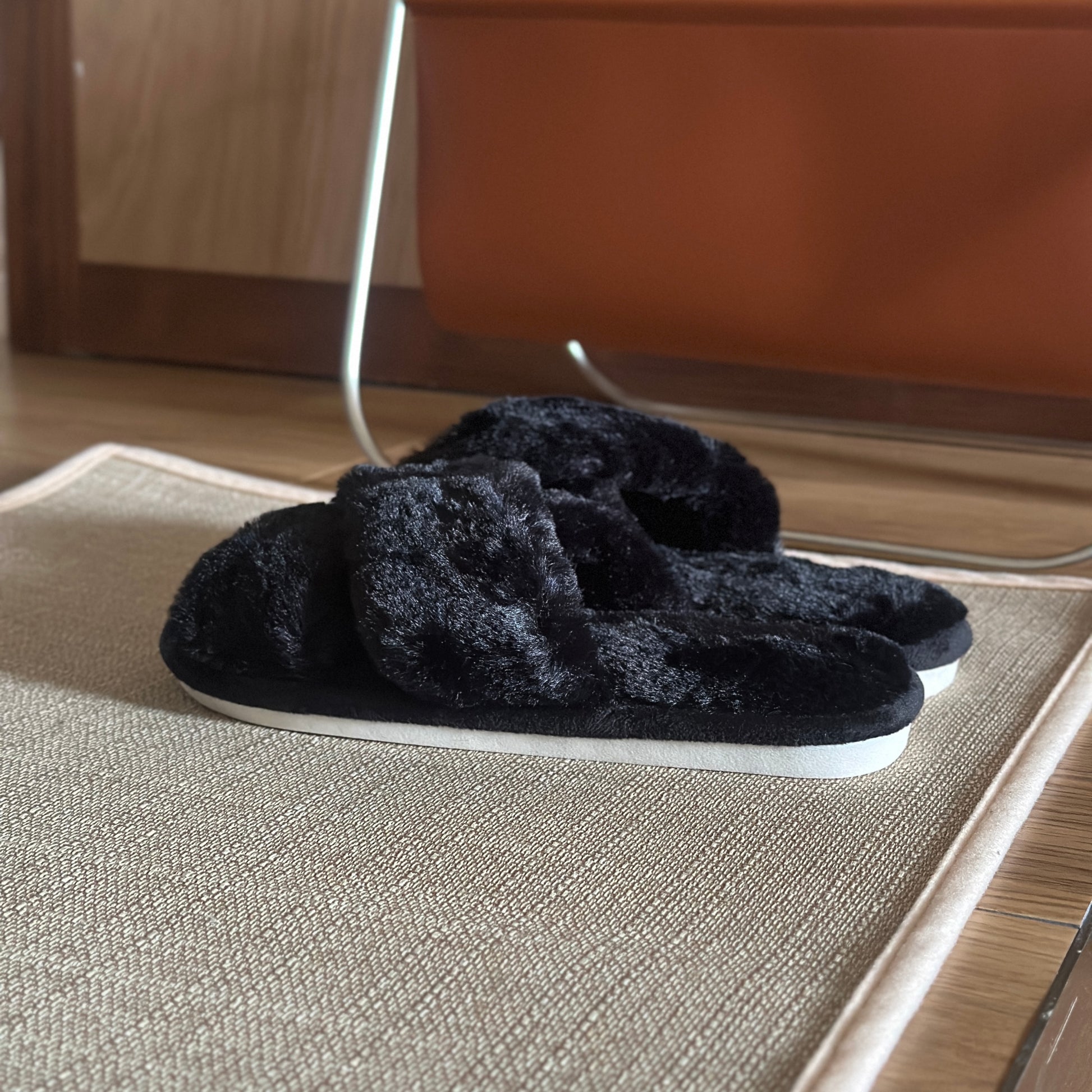 黒のファー素材のクロスされたスリッパを玄関で使っている様子
