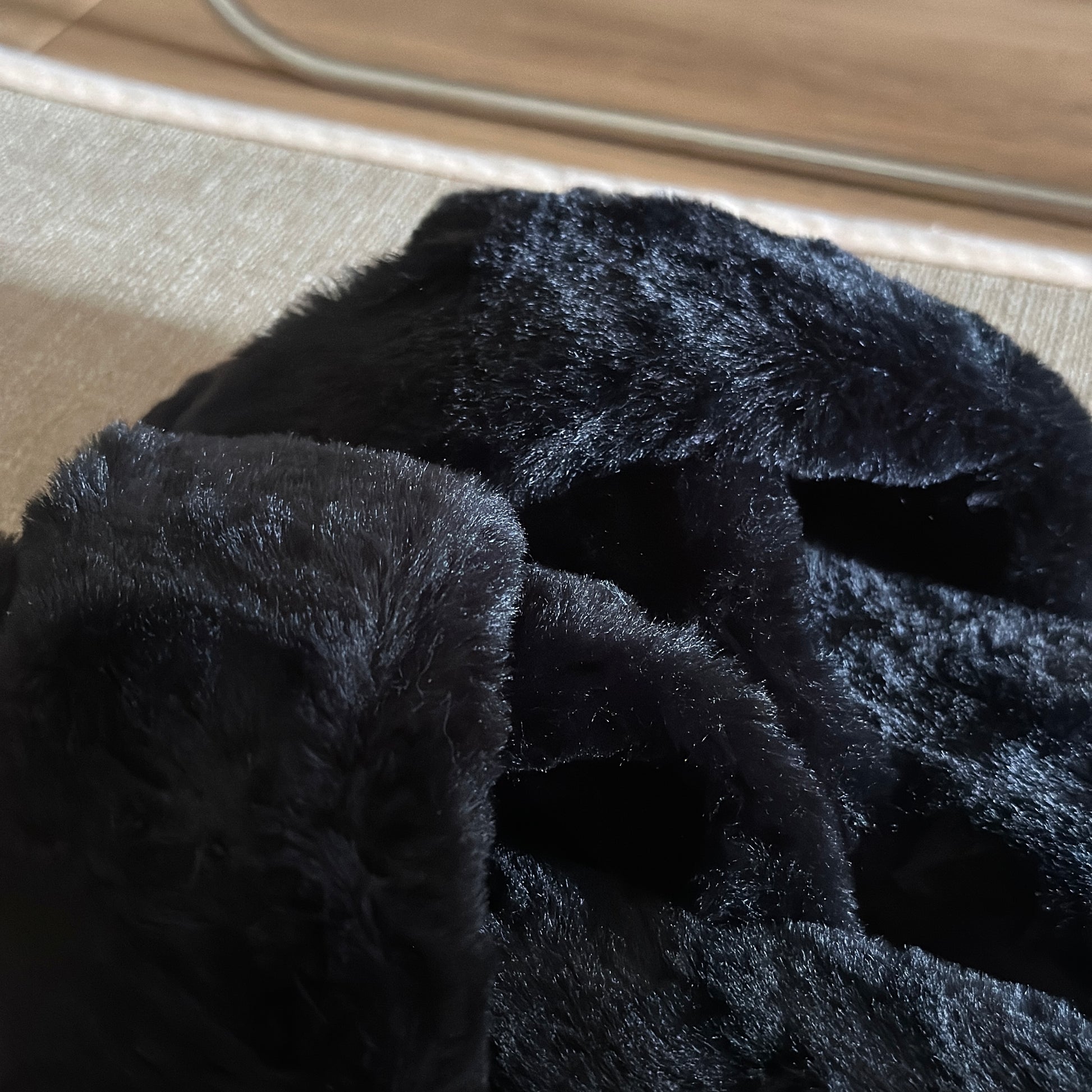 黒のファー素材のクロスされたスリッパをドアップで撮った様子