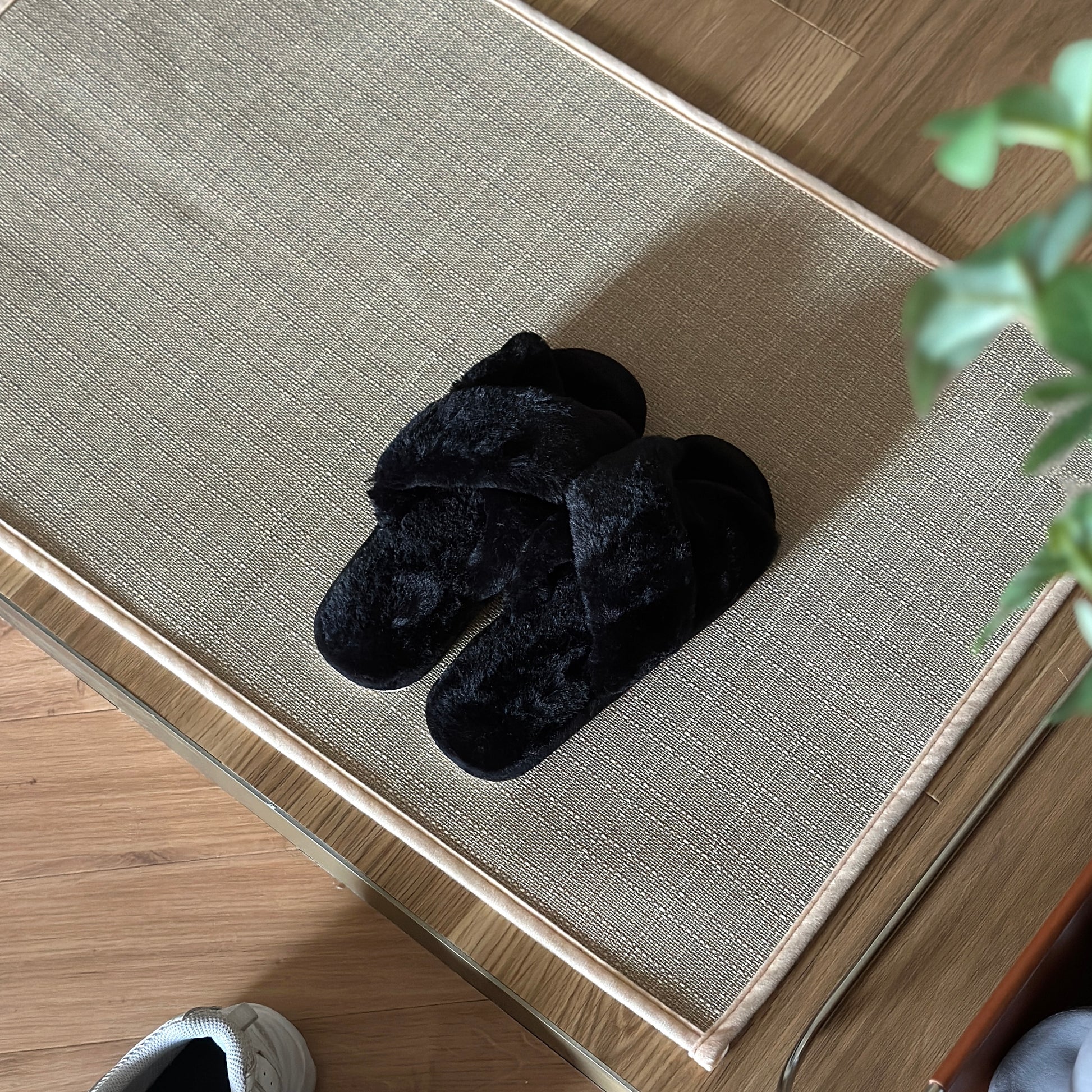 黒のファー素材のクロスされたスリッパを玄関で使っている様子