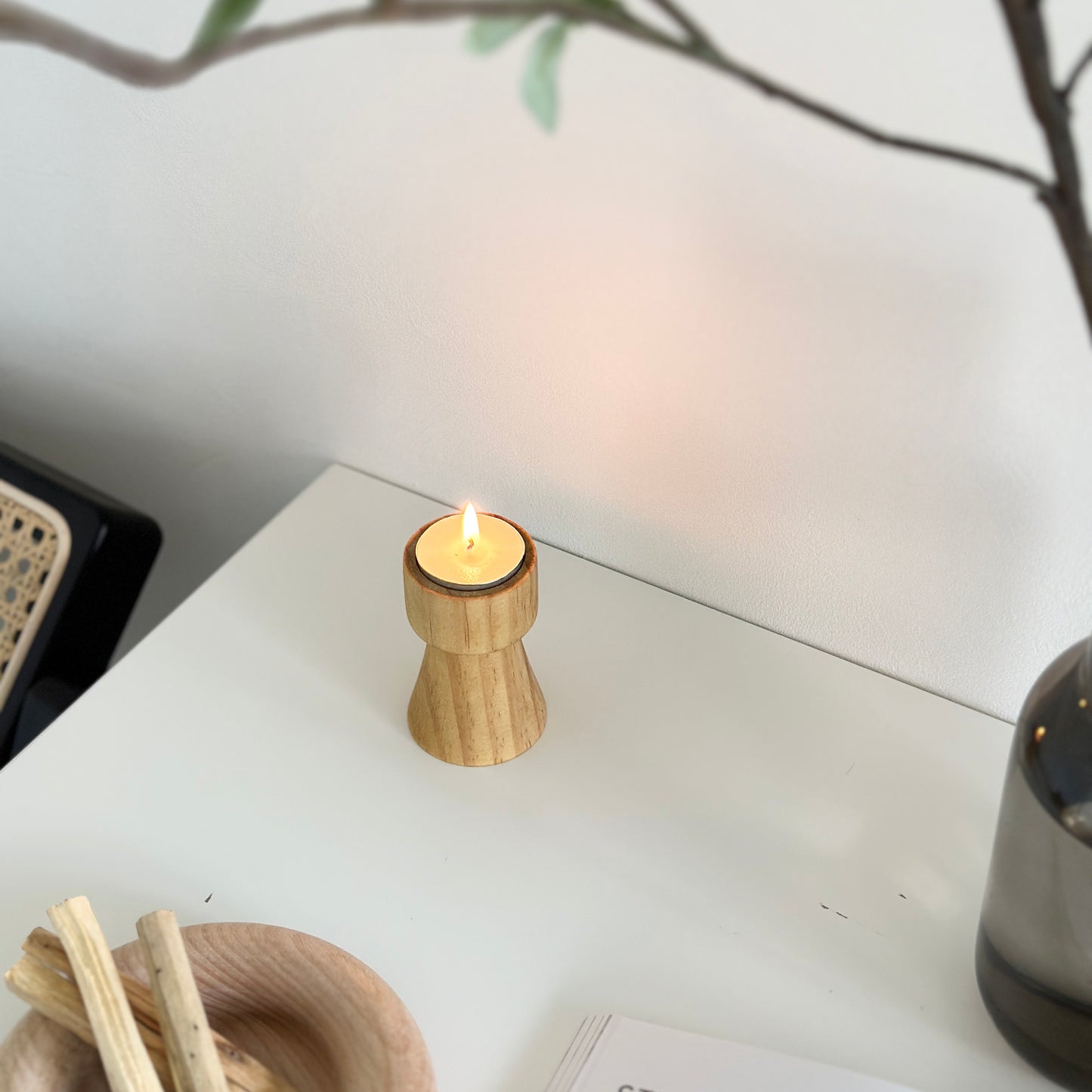ウッドブラウンの木製のミニキャンドルホルダーを上から映し、植物や木製のプレートが写り込んでいる写真