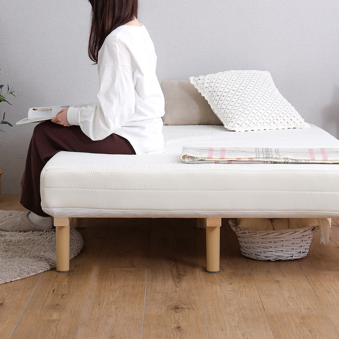 白のマットレス一体型ベッドに人が腰掛けている