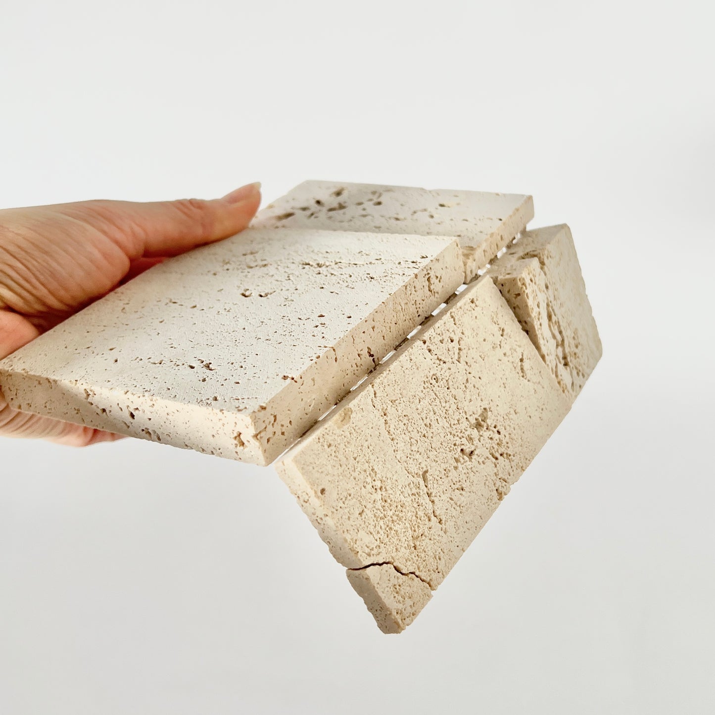 4つのプレートが組み合わさった大理石素材の大きめの正方形プレートの組み合わせ部分が折れ曲がる様子