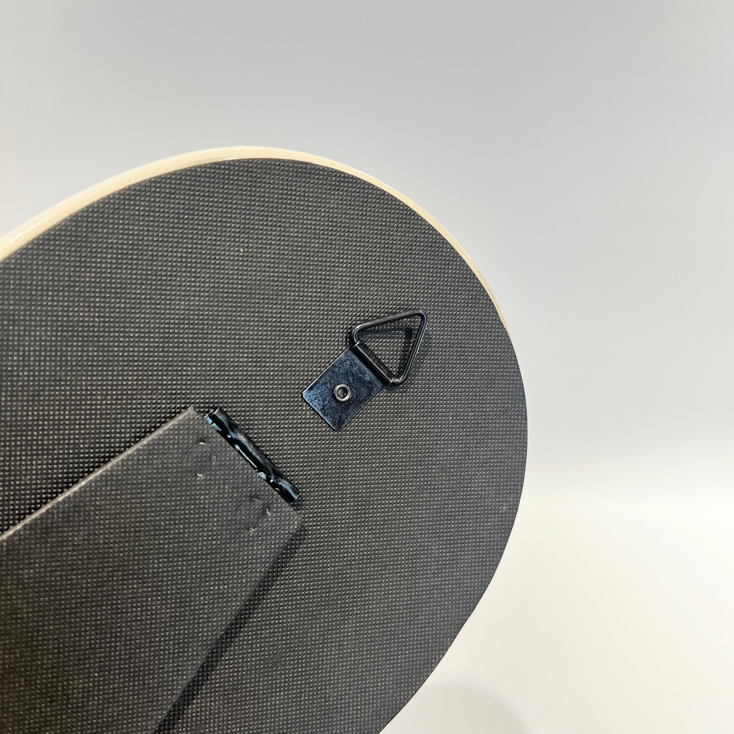 白い縁がぽってりしたフレームの卓上ミラーの裏面のフックのアップ