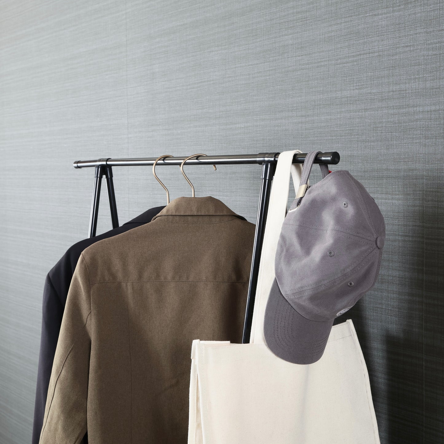 棚がついたオープンなハンガーラックに洋服やバッグが掛けられている様子