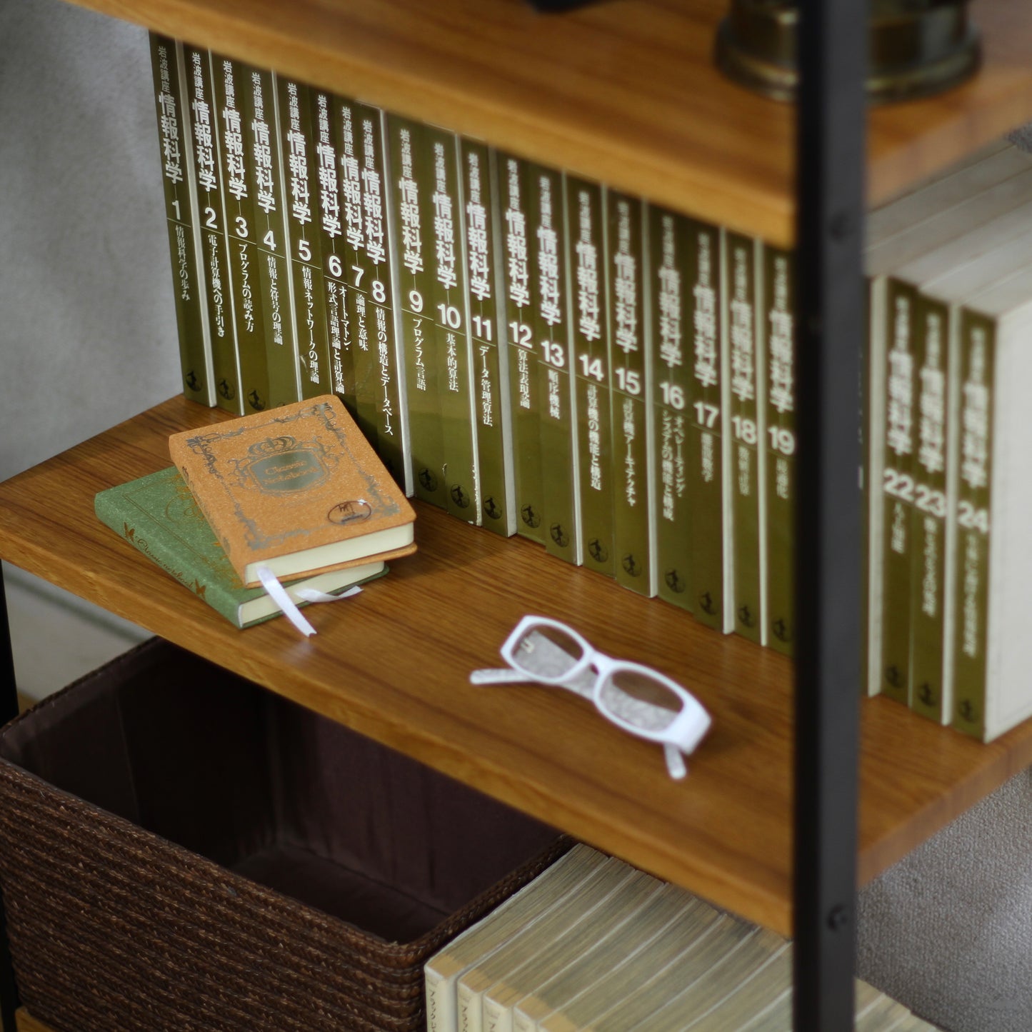 ウッド素材の天板と黒スチールのフレームの4段シェルフにほんと眼鏡が置かれている様子