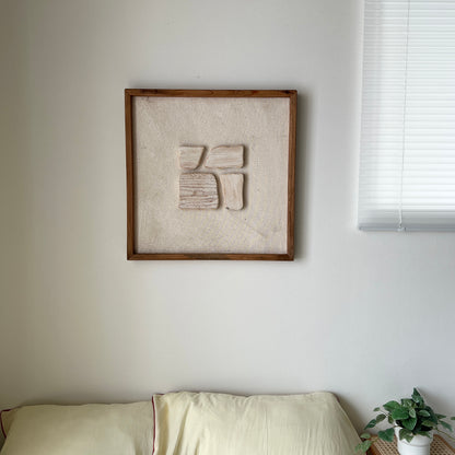 ベージュの立体的なウッドピースが貼り付けられたアートが壁にかかっている様子