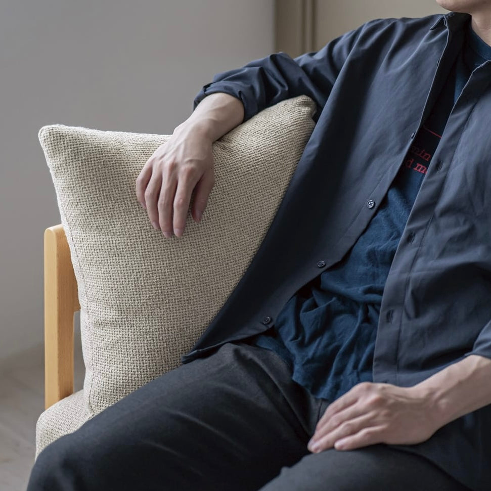 木製フレームのベージュのソファに人が座っている様子