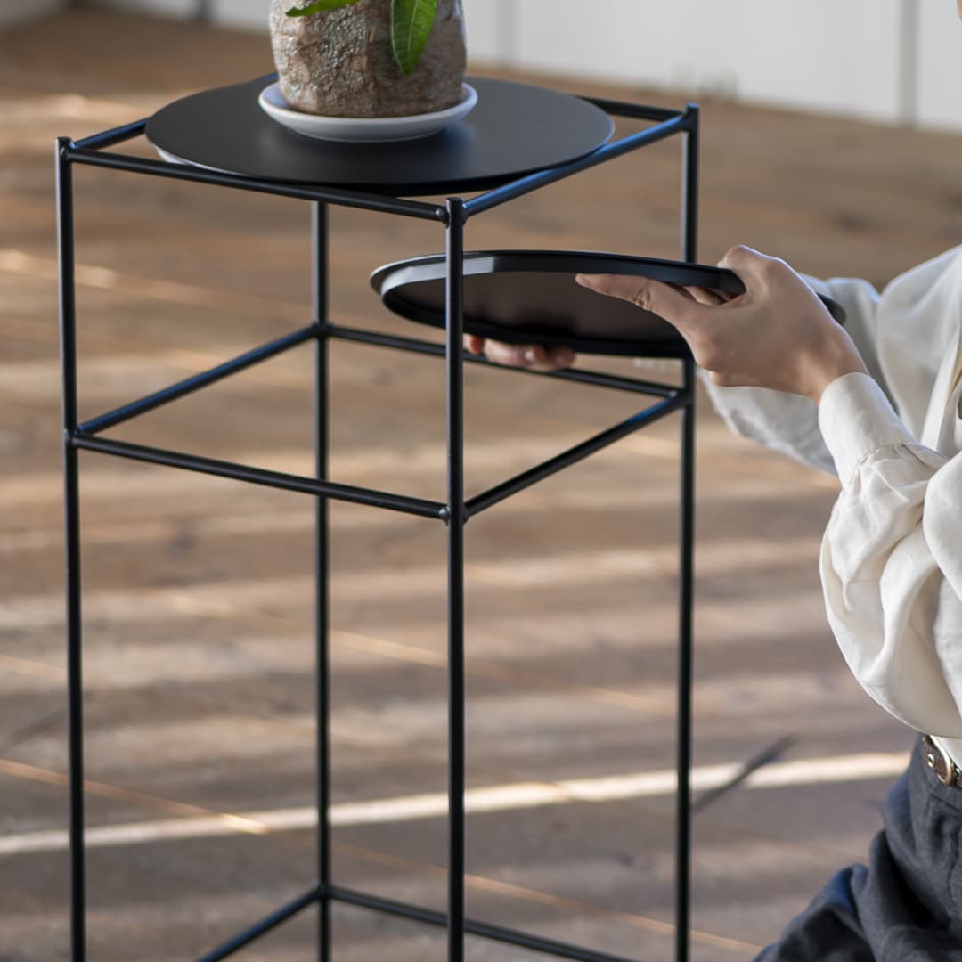 黒いスチールフレームのスクエアスチールラックで、丸い2段の棚に鉢植えと手で持ち上げる棚を備えています。